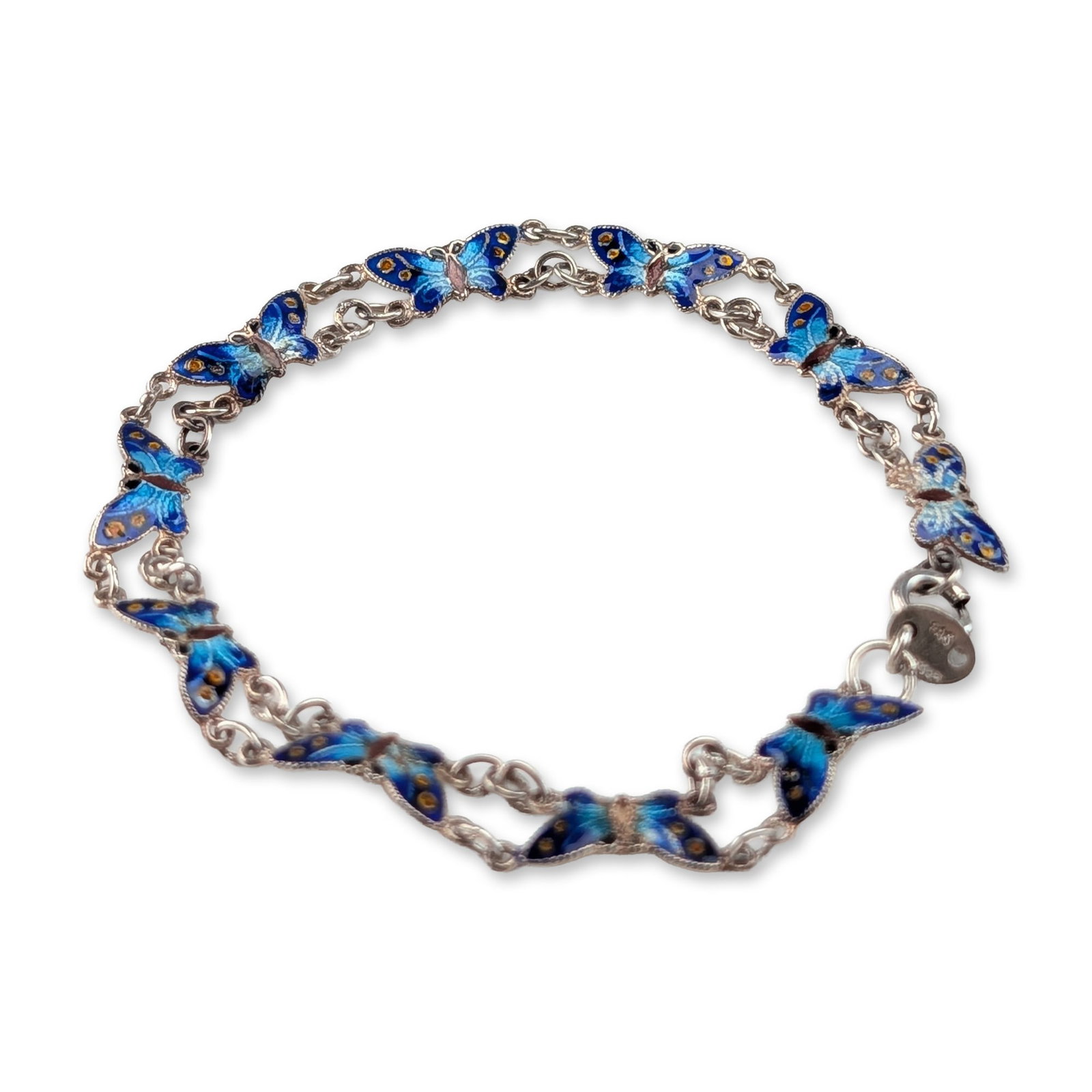 Sterling Silver Blue Enamel Butterfly Bracelet: Link bracelet in sterling silver featuring ten butterfly-shaped links. Each link is decorated with blue and light blue enamel with yellow accents on the wings, and a dark brown body. The silver edges 