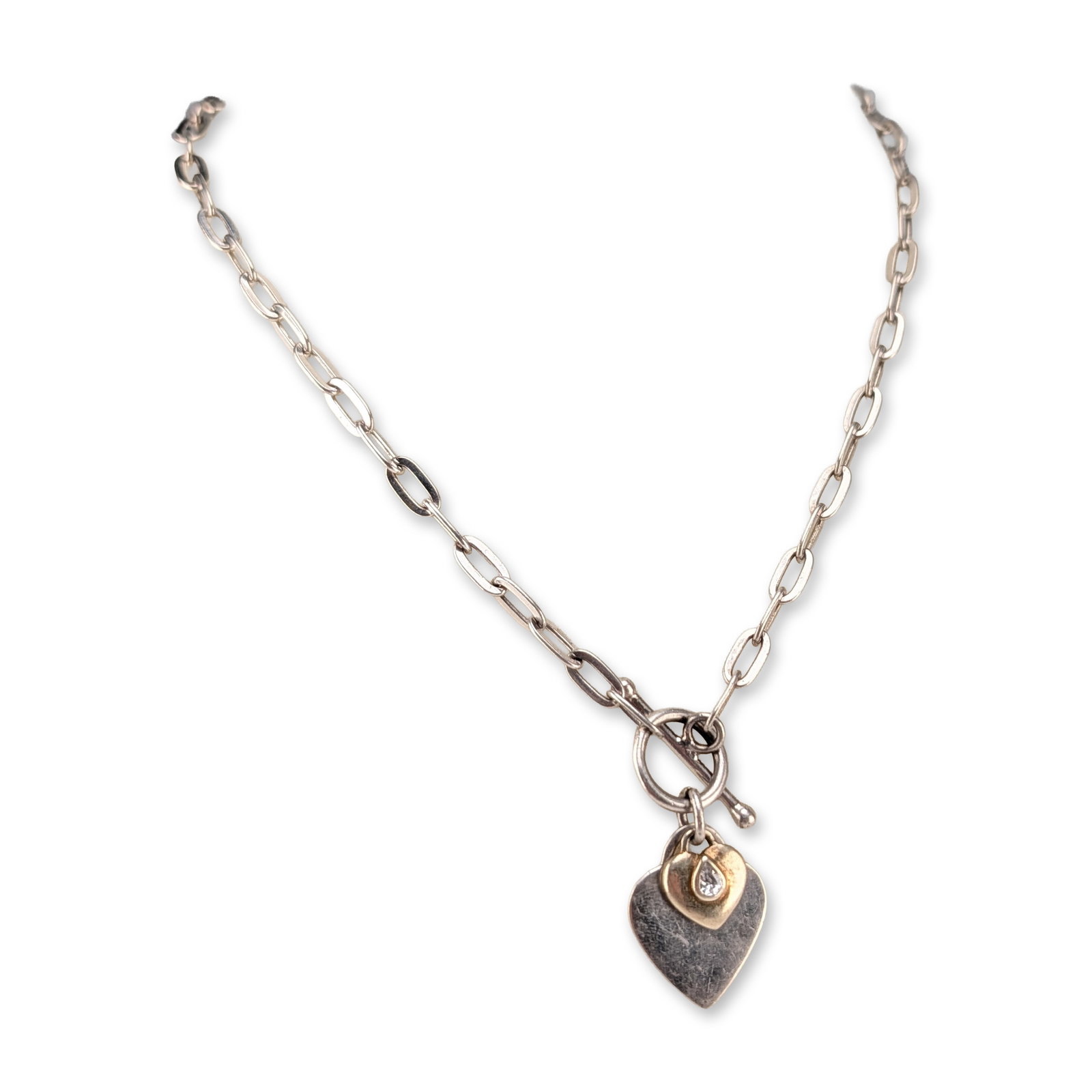 Sterling Silver Heart Pendant Necklace: A sterling silver long-link oval cable chain necklace with a toggle clasp and two heart pendants. The pendants consist of a large heart and a smaller heart featuring a bezel-set pear-cut colorless sto