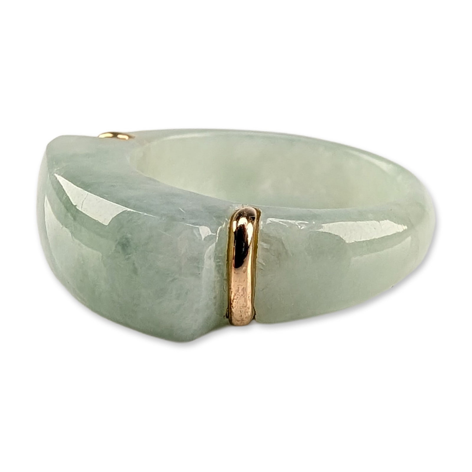 14K Yellow Gold and Jadeite Saddle Ring: Saddle ring carved from a single piece of mottled, translucent light green jadeite. The design features a flattened top and two 14k yellow gold wrap-around accents at the shoulders. The interior shank
