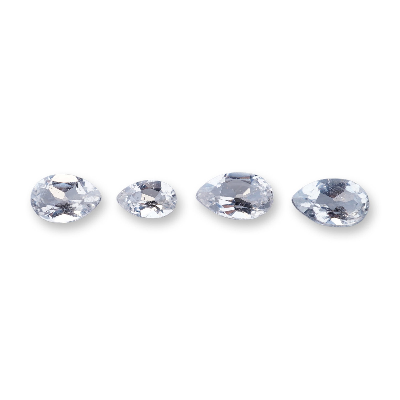 Set of Four Colorless Aquamarine Gemstones: Set of four colorless aquamarine gemstones, each fashioned in a pear-shaped brilliant cut. The stones are transparent with visible internal characteristics, including veils, internal fractures, and