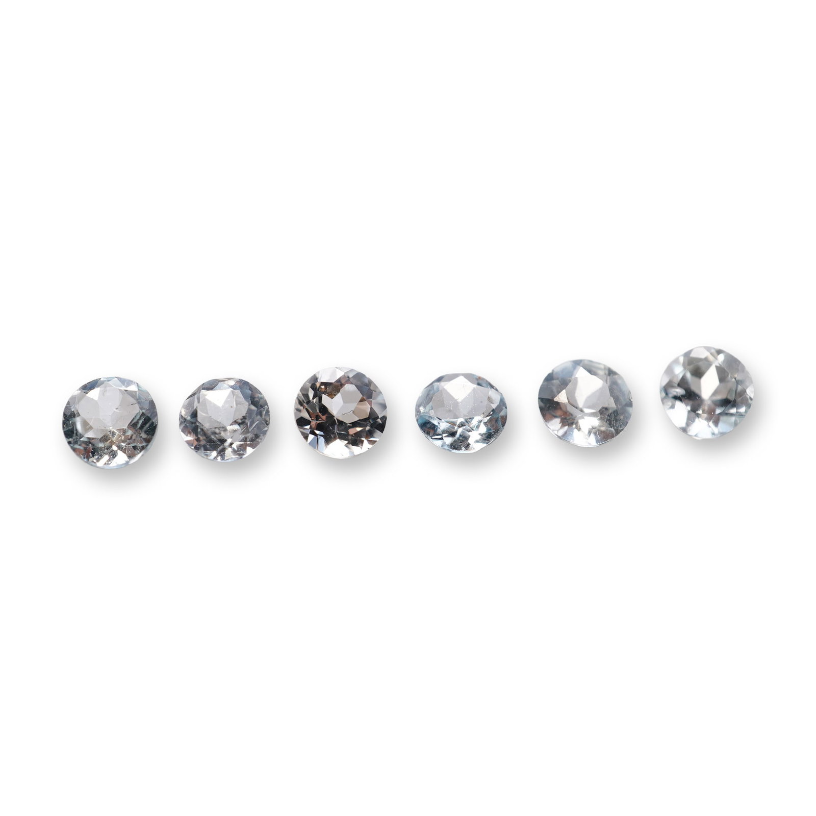 6pc Loose Round Cut Aquamarine Gemstones: Six loose gemstones appearing to be aquamarine. Each stone features a pale icy blue hue and faceted round-cut construction. The gemstone exhibits colors similar to aquamarine, and testing with a