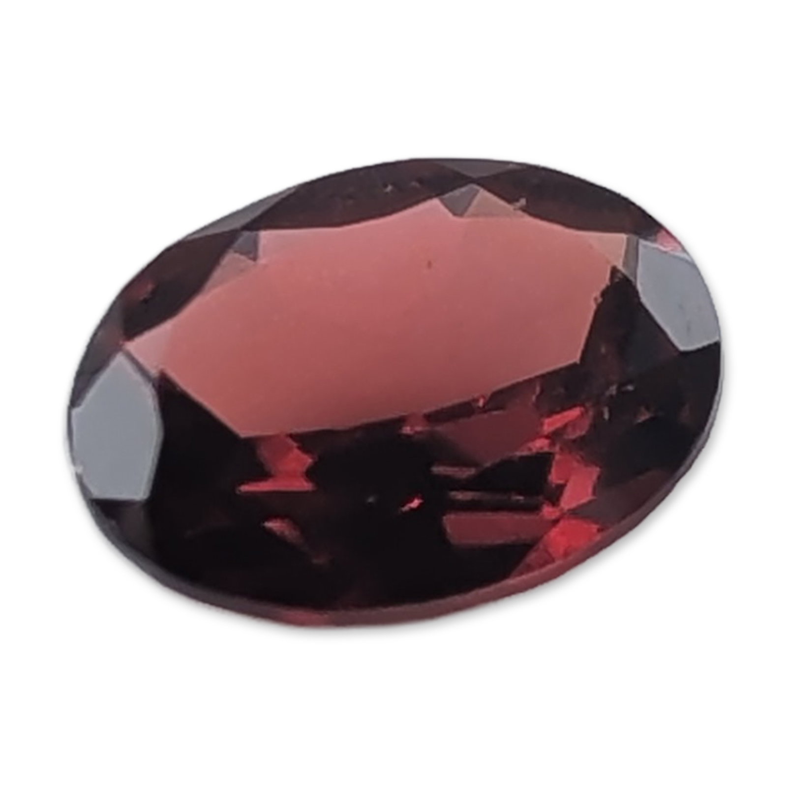 Oval Cut Deep Red Garnet Gemstone: Loose faceted red garnet gemstone. The stone exhibits a deep, saturated red color with secondary brownish-pink undertones and is worked in an oval faceted cut. Internal clarity appears eye-clean upon 
