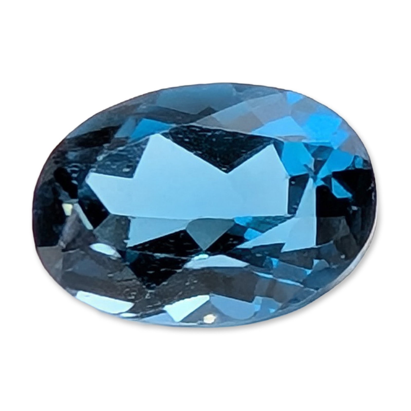 Oval London Blue Topaz Gemstone: A loose faceted gemstone of a saturated medium-dark blue hue that appears to be London blue topaz. The stone features an oval cut with a multi-faceted crown and pavilion. The clarity is high with no e