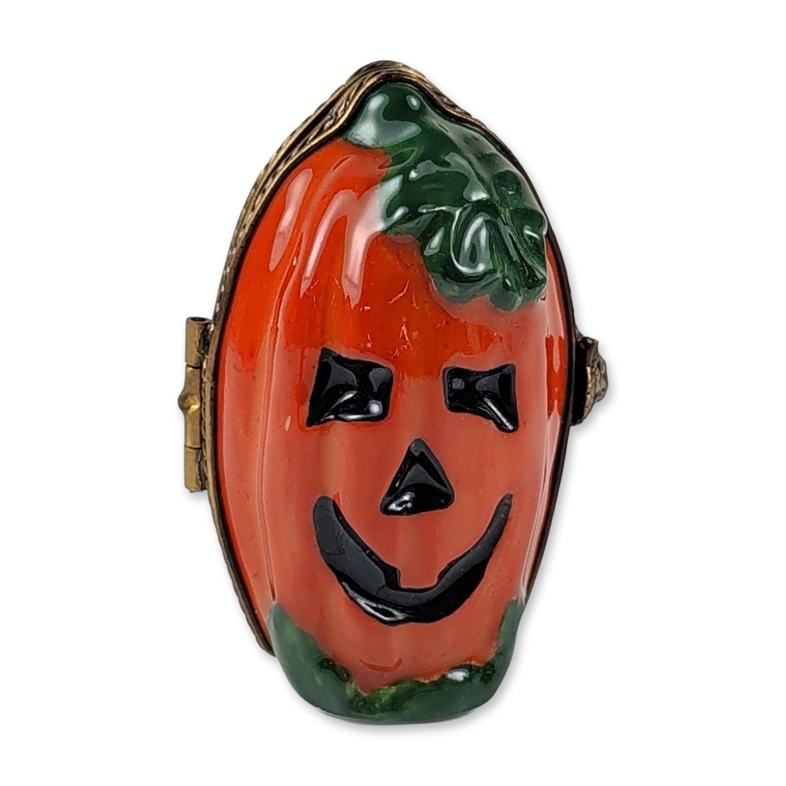 Limoges Porcelain Halloween Pumpkin Box: Limoges hand-painted porcelain trinket box modeled in the form of a jack-o-lantern. The exterior features orange enamel with black facial features and green foliage accents, joined by a bronze-tone me