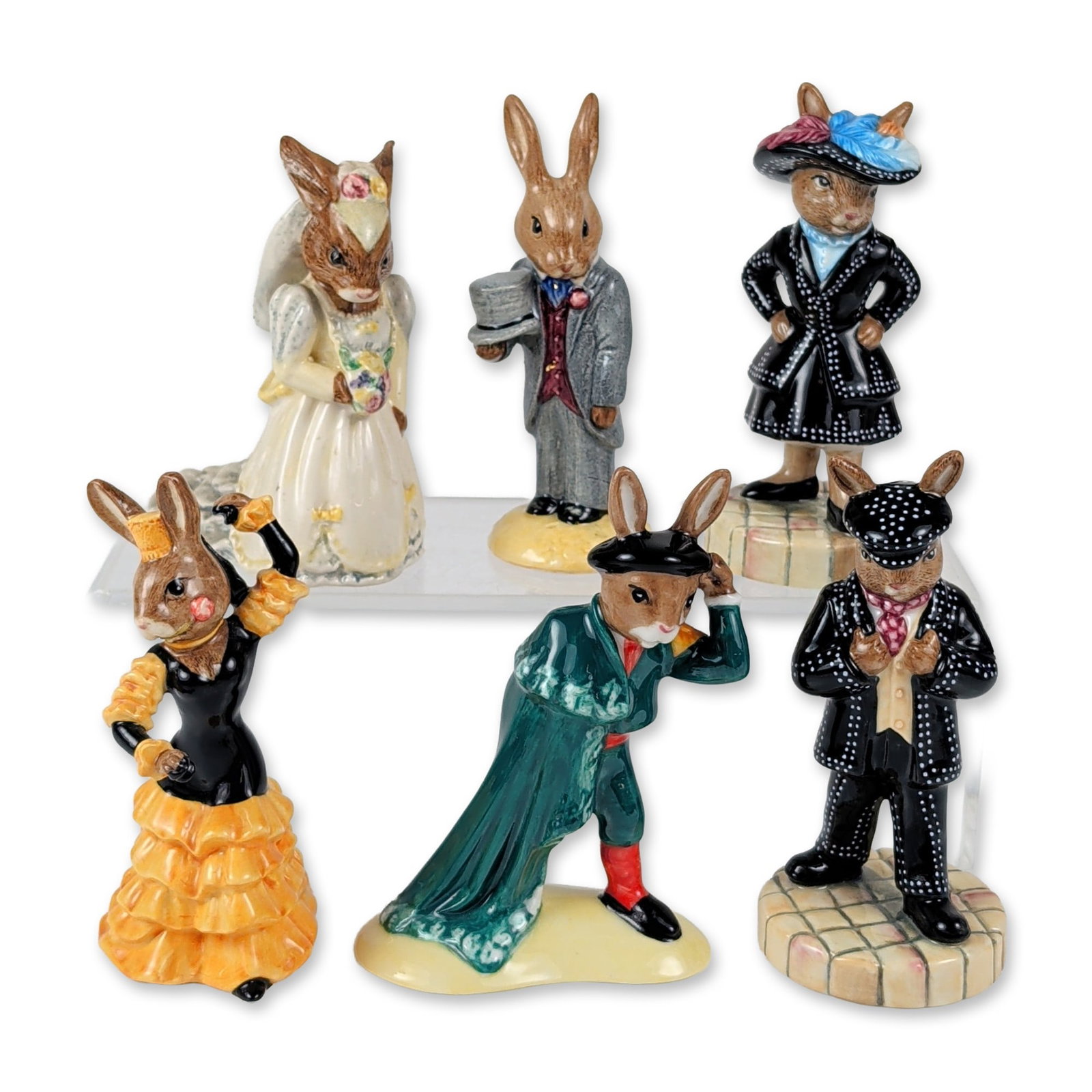 6pc Royal Doulton Bunnykins Ceramic Figurines: This six-piece collection of English hand-painted glazed ceramic Bunnykins figures highlights anthropomorphic rabbits in diverse regional costumes and formal celebration attire. The grouping features 
