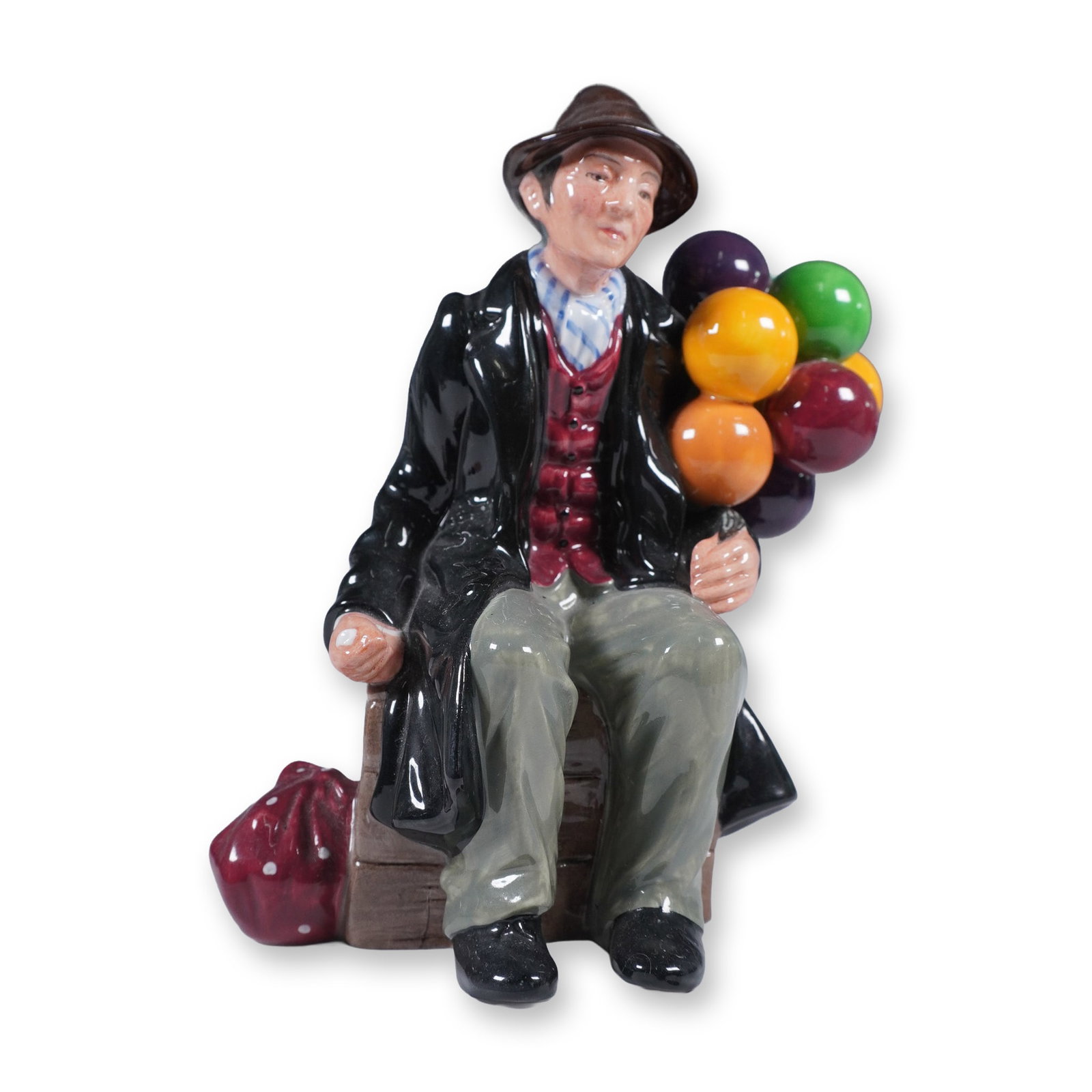Royal Doulton Porcelain Figurine, The Balloon Man HN1954: This hand-painted porcelain figurine by Royal Doulton features The Balloon Man, a charming character seated on a wooden crate with a bundle of brightly colored balloons. Modelled by Leslie Harradine, 