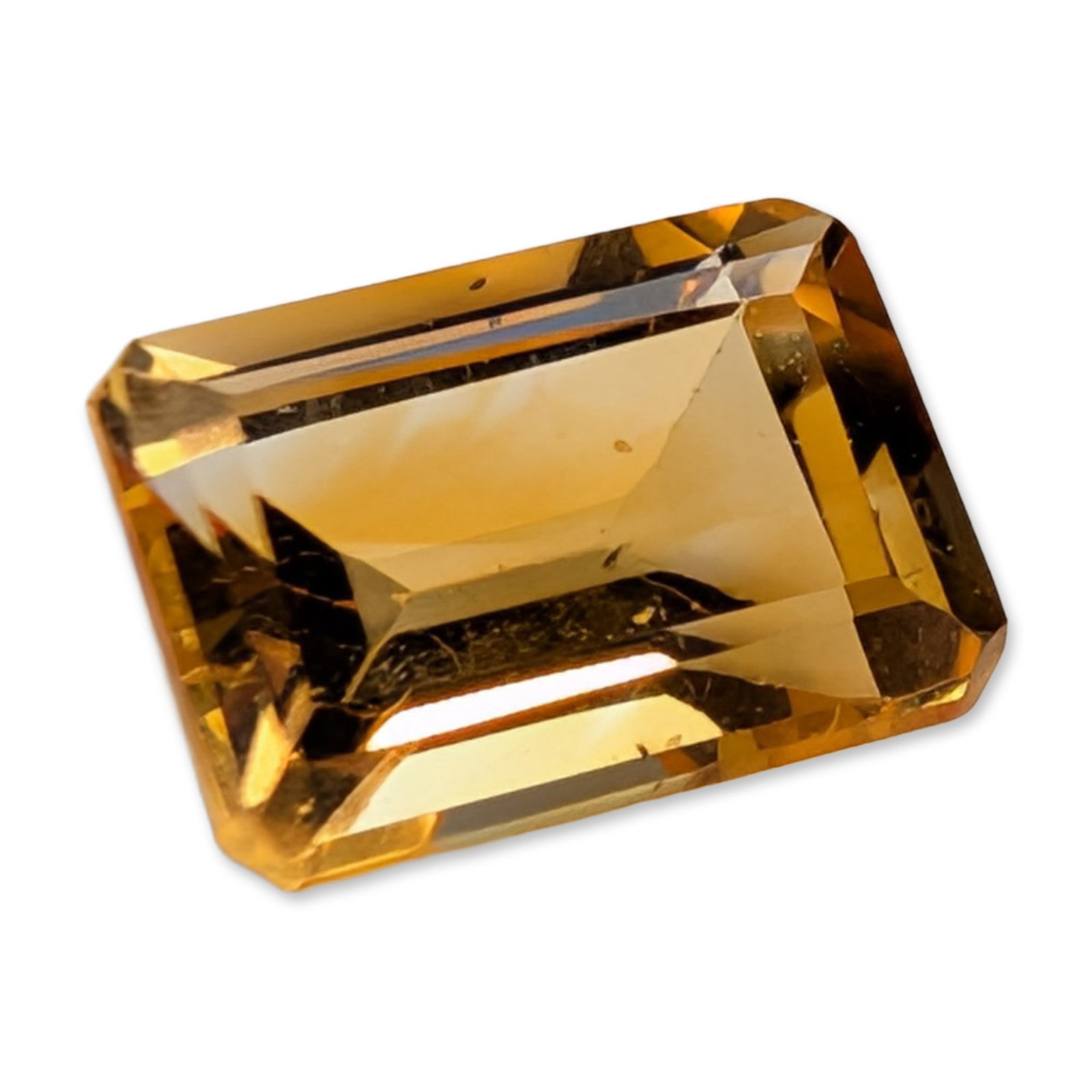 Emerald Cut Golden Yellow Faceted Citrine Gemstone: A loose faceted citrine gemstone, featuring a saturated golden-yellow to honey-orange hue. The stone is worked in a rectangular emerald cut with clipped corners and step-cut facets. Internal character