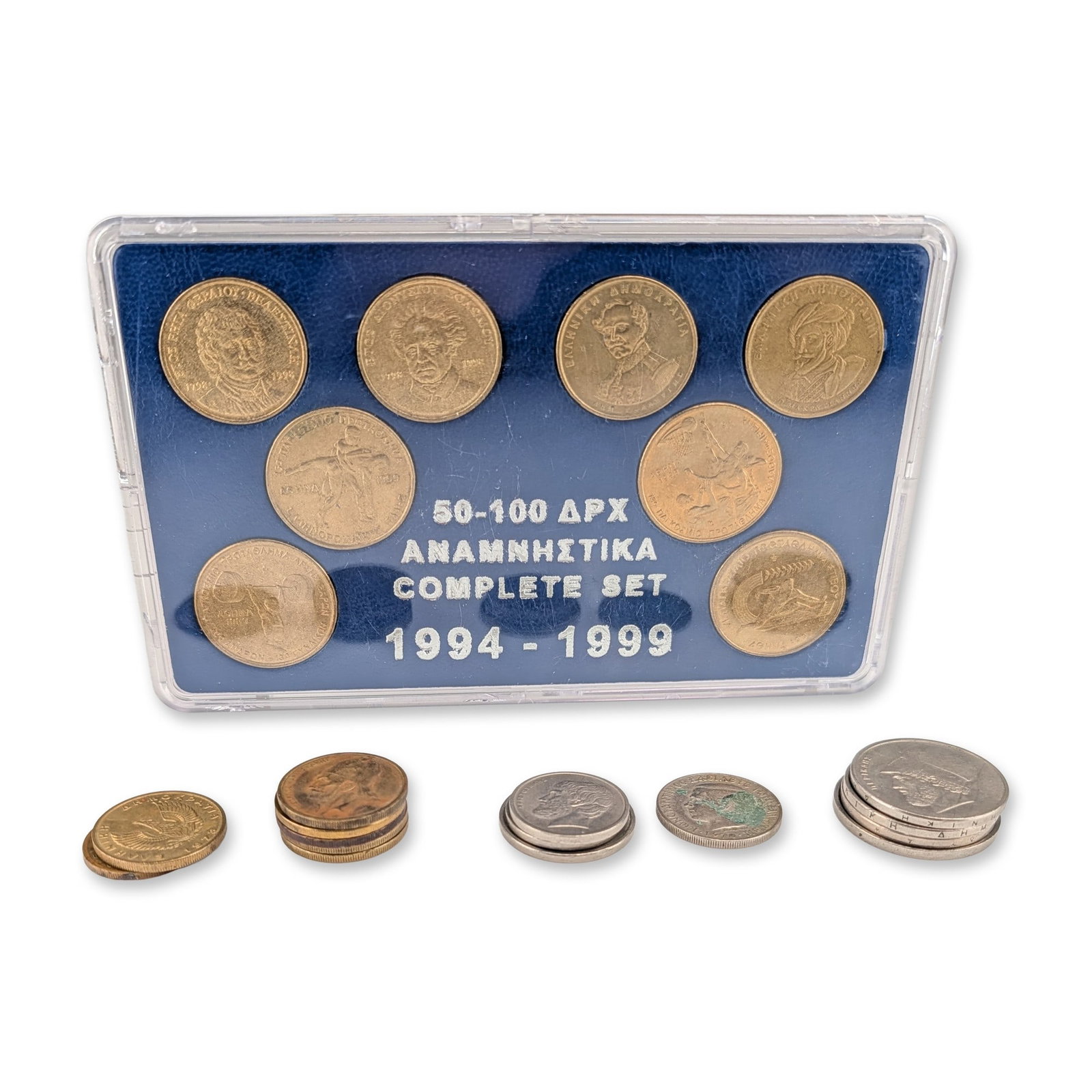 16pc Collection of Greek Drachmae Commemorative Set and Circulation Coins: A collection of Greek drachmae coins featuring a cased set of eight 50 and 100 drachmae commemoratives dating from 1994 to 1999. The coins are housed in a blue plastic presentation case with a label r