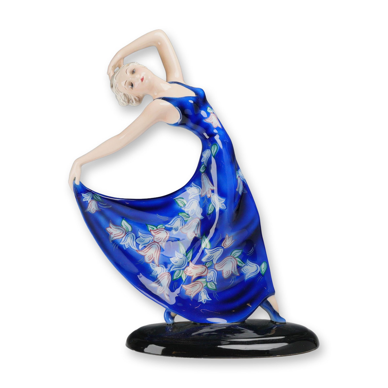 Goldscheider by Josef Lorenzl Dancer Figurine: Porcelain dancer sculpture designed by Josef Lorenzl, depicting a poised female figure holding the edge of her flowing blue dress adorned with bell-shaped flowers in her right hand. She stands gracefu