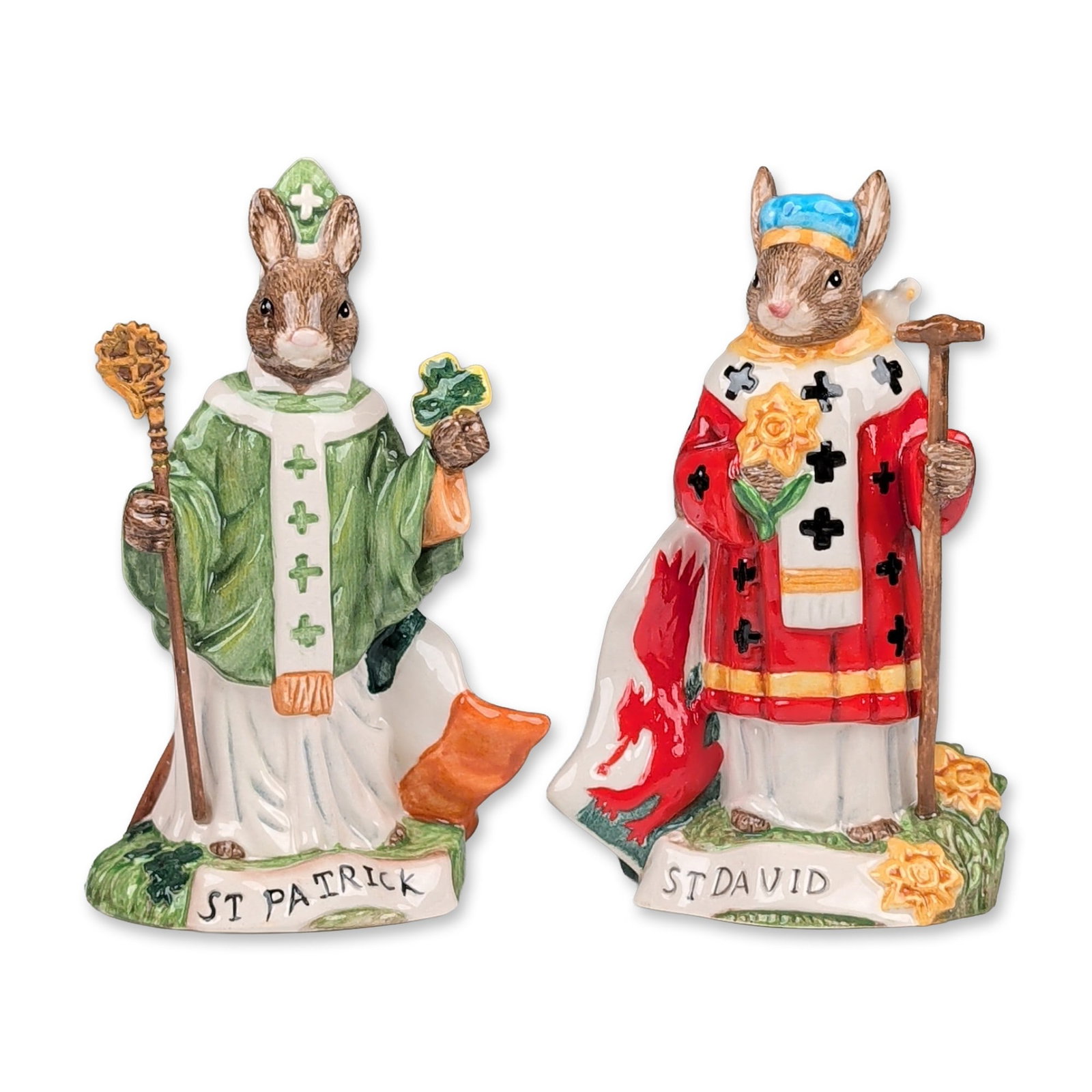 2pc Royal Doulton Bunnykins Patron Saints Figurines, Saint Patrick (DB397) & St. David (DB400): The St. Patrick, limited edition 608 of 1000, figure wears green and white ecclesiastical robes, holding a shamrock and a golden crosier, with an Irish tricolor flag motif on the base reverse. The St.