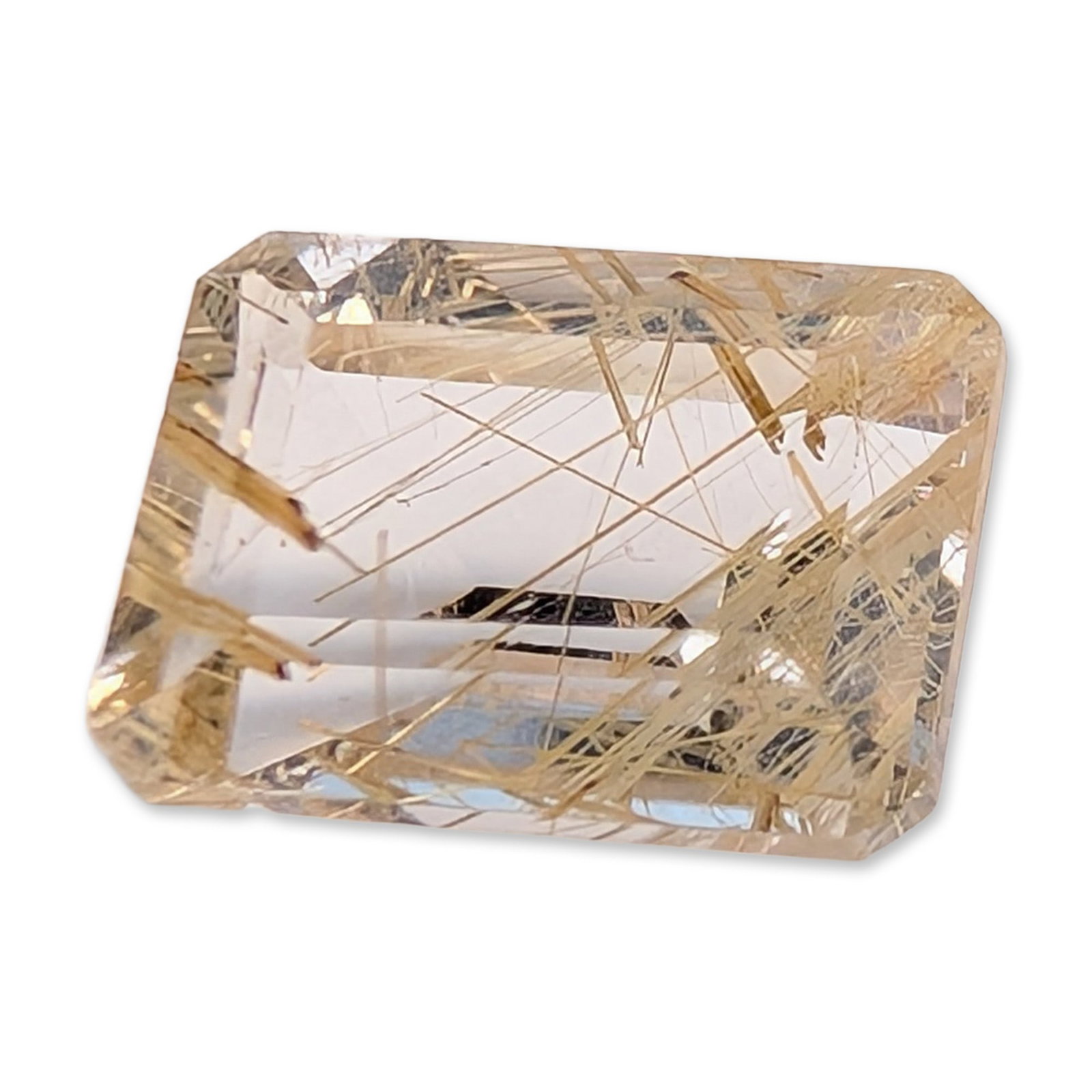 Emerald-Cut Rutilated Quartz Gemstone: Loose gemstone appearing to be natural rutilated quartz. The specimen features a colorless, transparent host with a high density of randomly oriented golden-yellow rutile needle inclusions. The stone