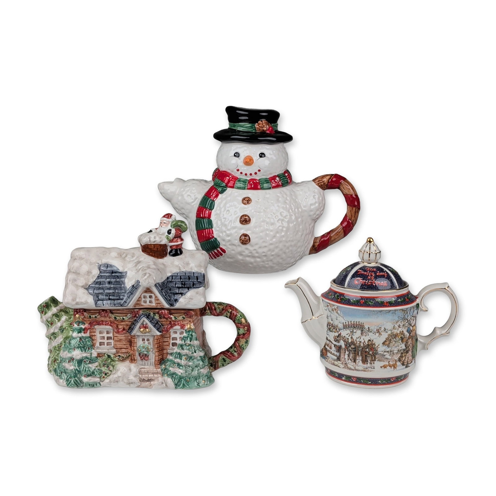 3pc Holiday Themed Ceramic Teapots: Collection of decorative ceramic teapots featuring winter and holiday motifs. A Heritage Mint Ltd molded earthenware figural teapot is shaped as a snow-covered log cabin with an evergreen tree spout, 