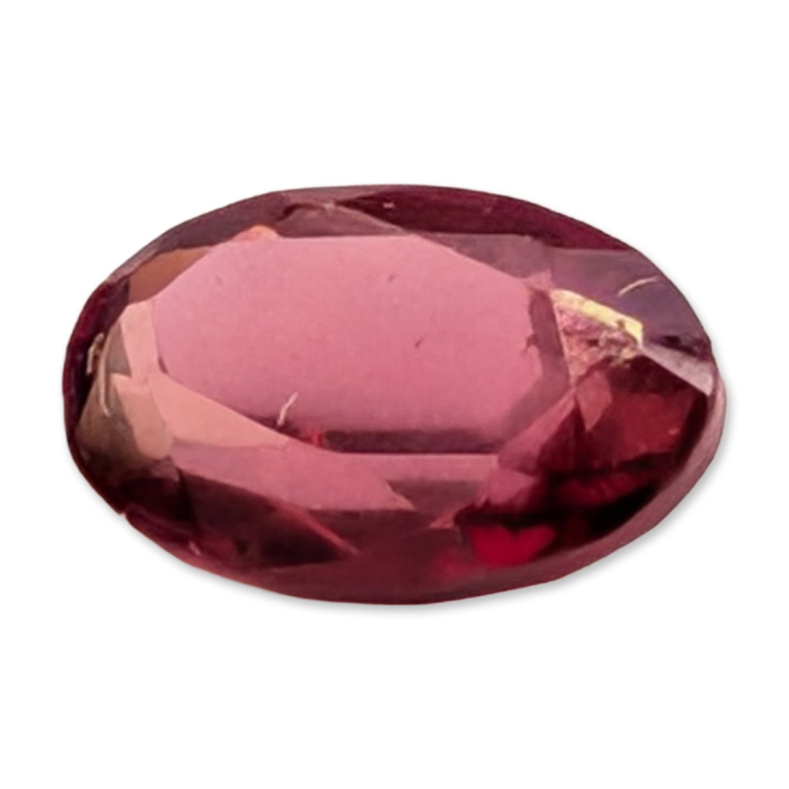 Loose Oval Cut Purplish Red Gemstone: Loose oval faceted gemstone, appearing to be a variety such as pink tourmaline or rhodolite garnet. The stone exhibits a saturated purplish-red to raspberry pink hue. The cut features a standard crown