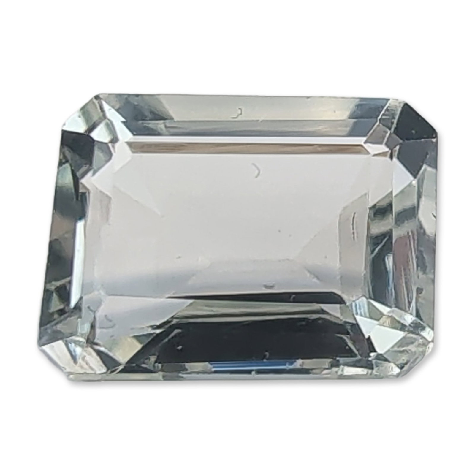 Emerald-Cut Pale Blue Loose Aquamarine Gemstone: Rectangular emerald-cut loose aquamarine gemstone exhibiting a pale blue to near-colorless hue. It features a step-cut facet arrangement with truncated corners and an open table, showing high clarity 