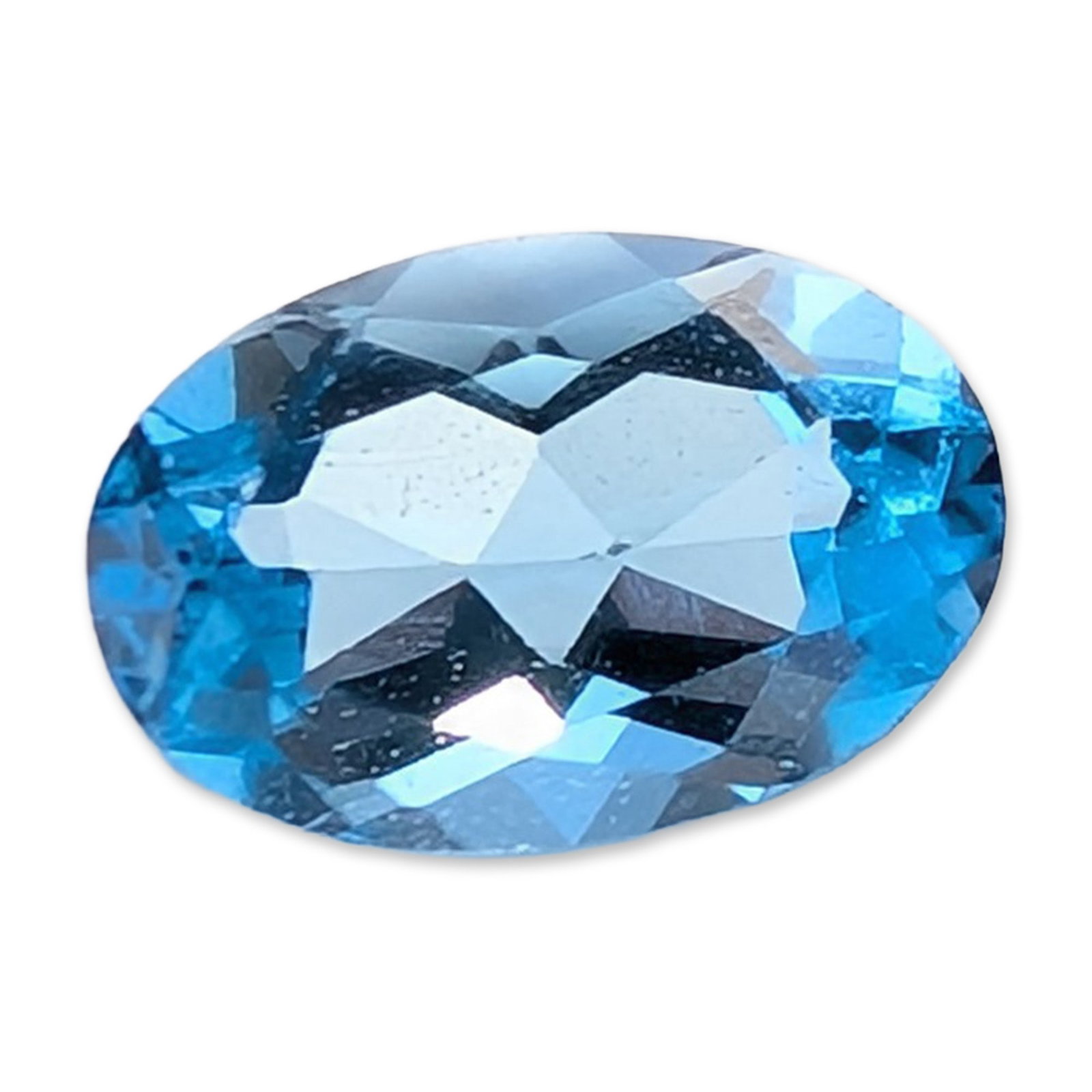 Blue Topaz Oval Cut Gemstone: Single loose faceted topaz gemstone, featuring an oval brilliant-style cut. The stone exhibits a light blue hue with even color saturation and eye-clean clarity. Facet junctions appear sharp and symme