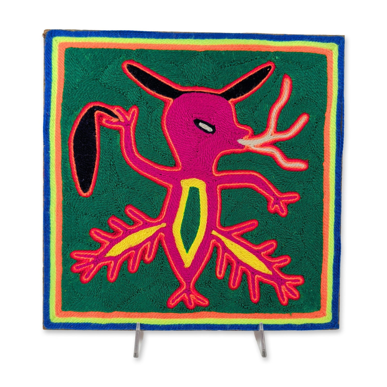 Huichol Mexican Yarn Painting Panel: Huichol, Mexico. Traditional yarn painting on masonite panel, featuring a central stylized zoomorphic figure in magenta yarn with white antlers and yellow-outlined appendages. The central figure conta
