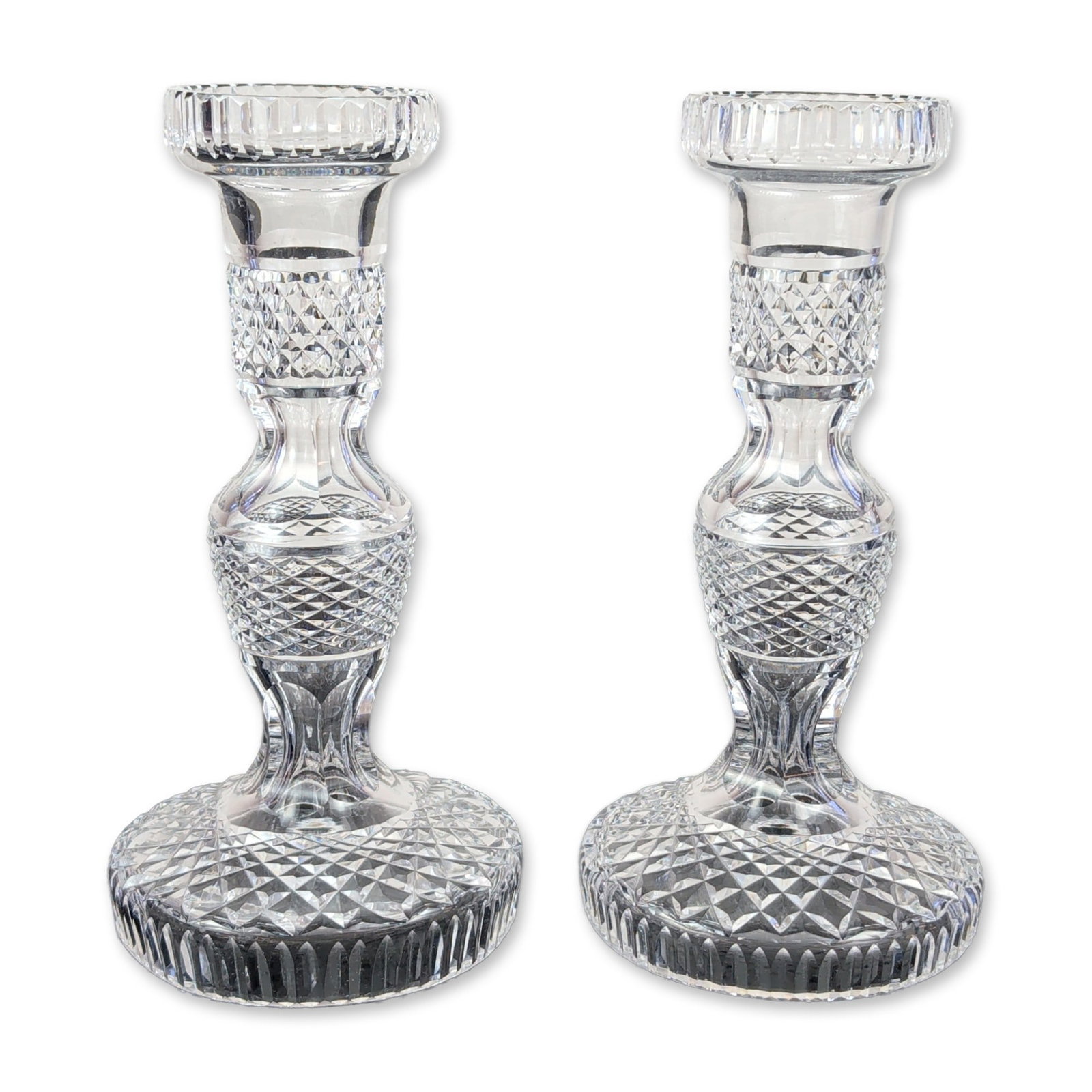 Pair of Waterford Cut Crystal Alana Candlesticks: Waterford cut lead crystal candlesticks in the Alana pattern. Each piece features a multi-tiered faceted stem centered by a diamond-cut knop and topped with a flared nozzle decorated with vertical flu