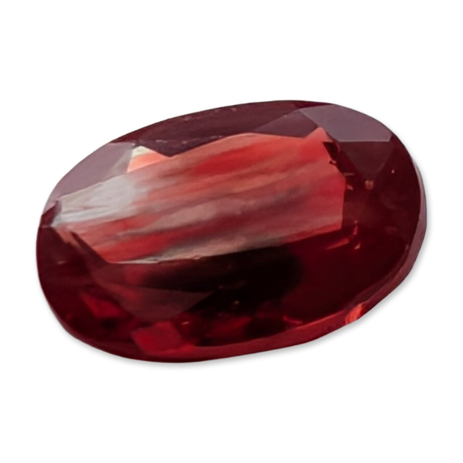 Oval Cut Red Stone: A loose faceted stone, featuring a deep red hue. The stone is worked into an oval faceted cut. Visual inspection reveals internal characteristics including distinct color zoning and fine, silk-like ru
