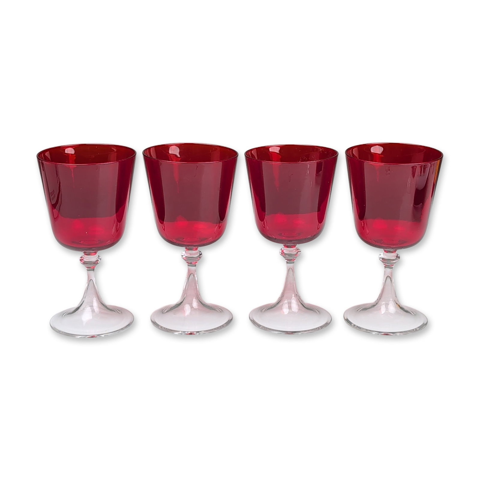 Set of Four Ruby Red Glass Goblets: Vintage glass goblets featuring deep ruby red translucent bowls fused to clear crystal stems and circular bases. The hand-blown bowls are designed with a slightly tapered, rounded profile and fire-pol