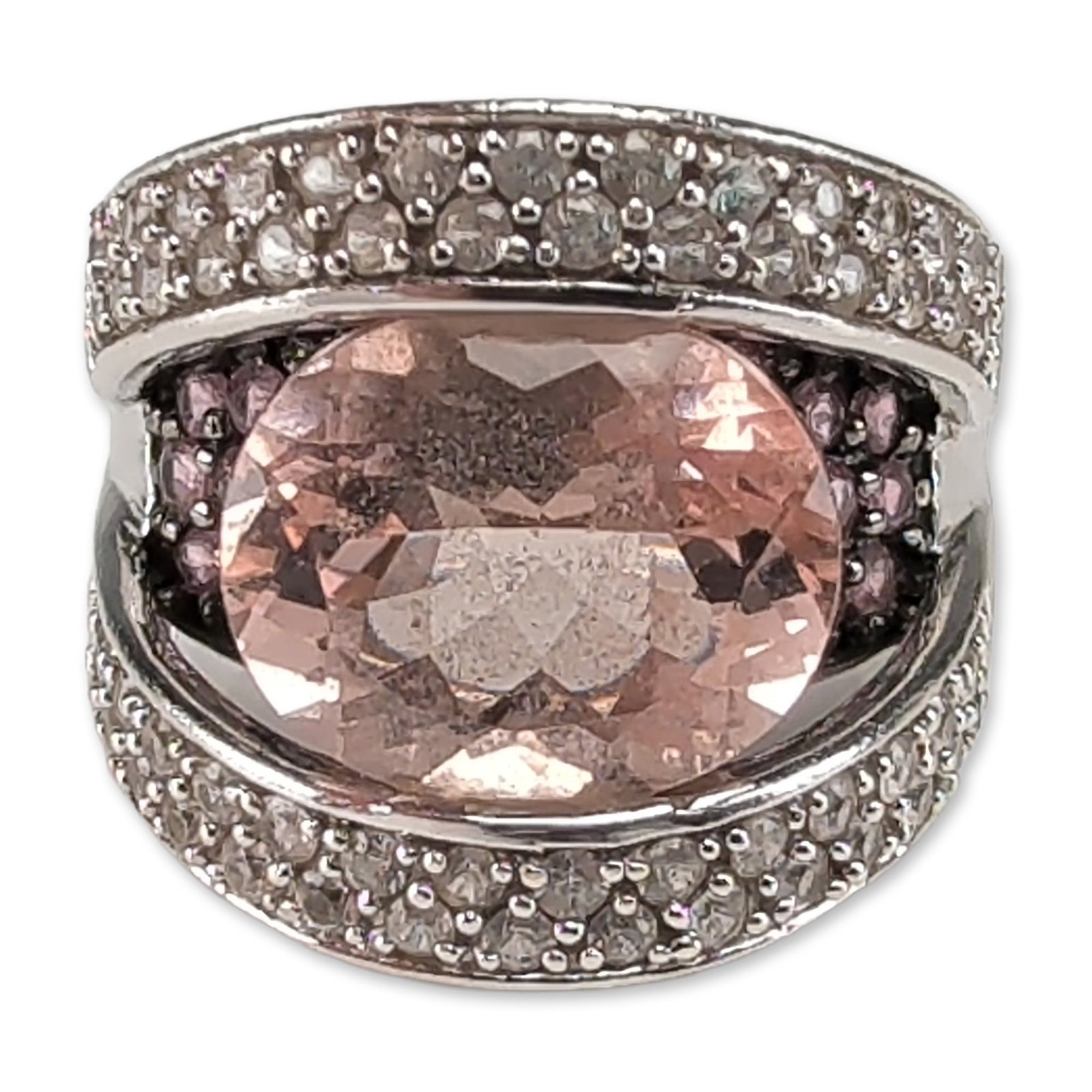 14K White Gold Morganite and Sapphire Ring: Contemporary cocktail ring in 14k white gold, featuring a large oval-cut light peachy-pink center gemstone. The architectural split-shank design consists of two outer bands pave-set with small round