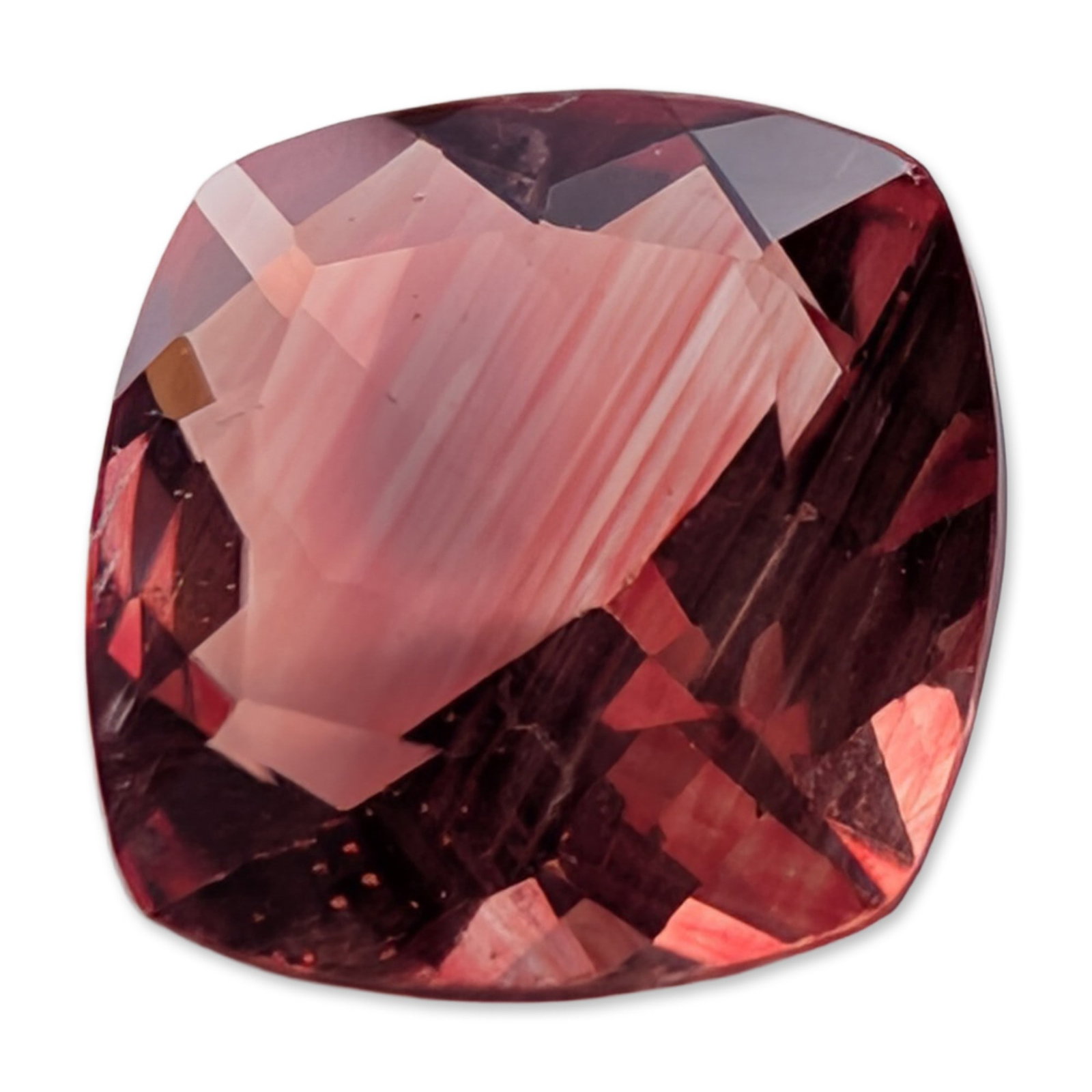 Reddish Pink Cushion Cut Faceted Stone: A loose cushion cut faceted stone featuring a reddish-pink hue with orangey-peach undertones and medium-strong saturation. Internal characteristics include prominent parallel linear needle-like