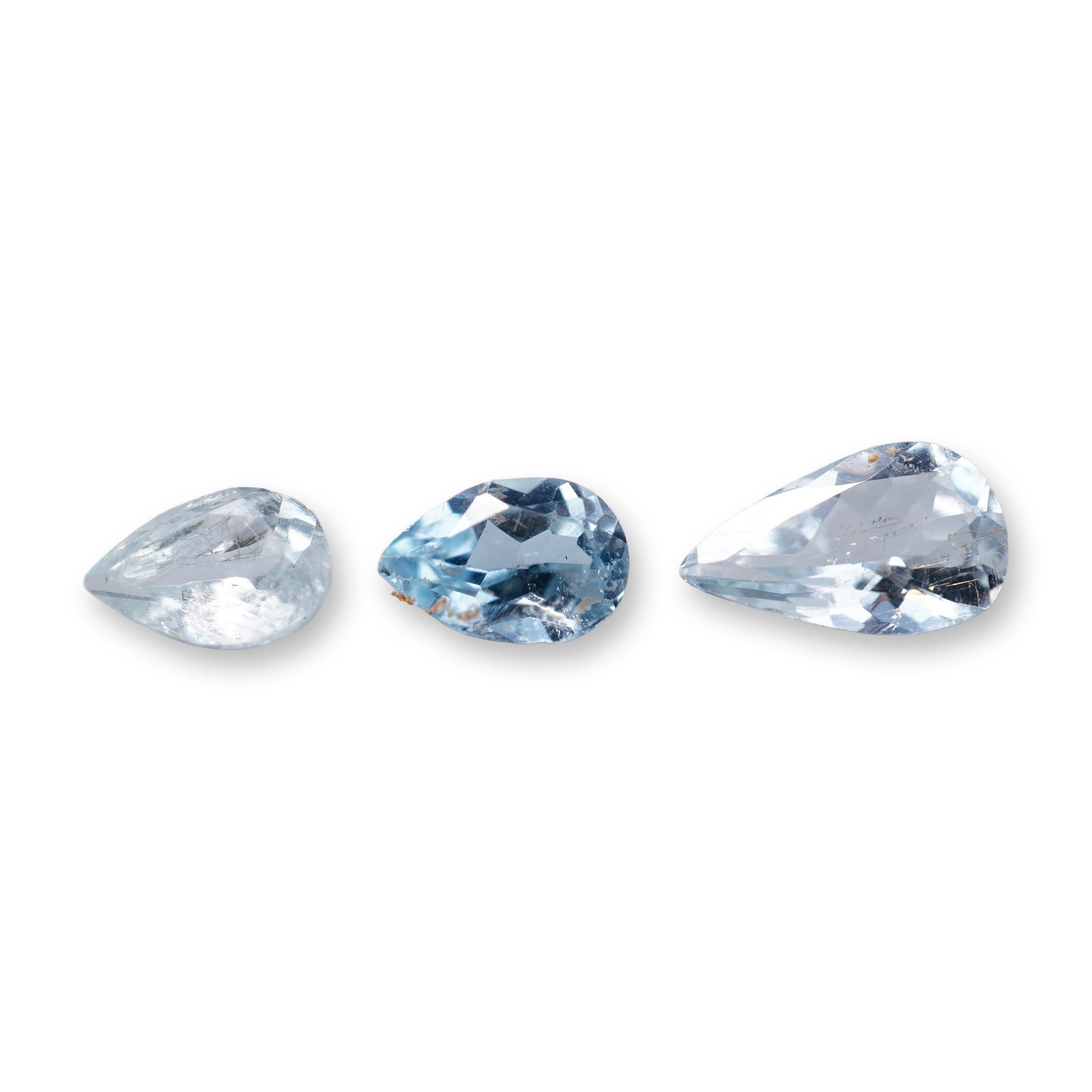 Three Pear Faceted Aquamarine Gemstones: Trio of pear faceted aquamarine gemstones, featuring a range of hues from near-colorless to light sky blue. The stones are fashioned in teardrop proportions with faceted crowns and pavilions. Physical