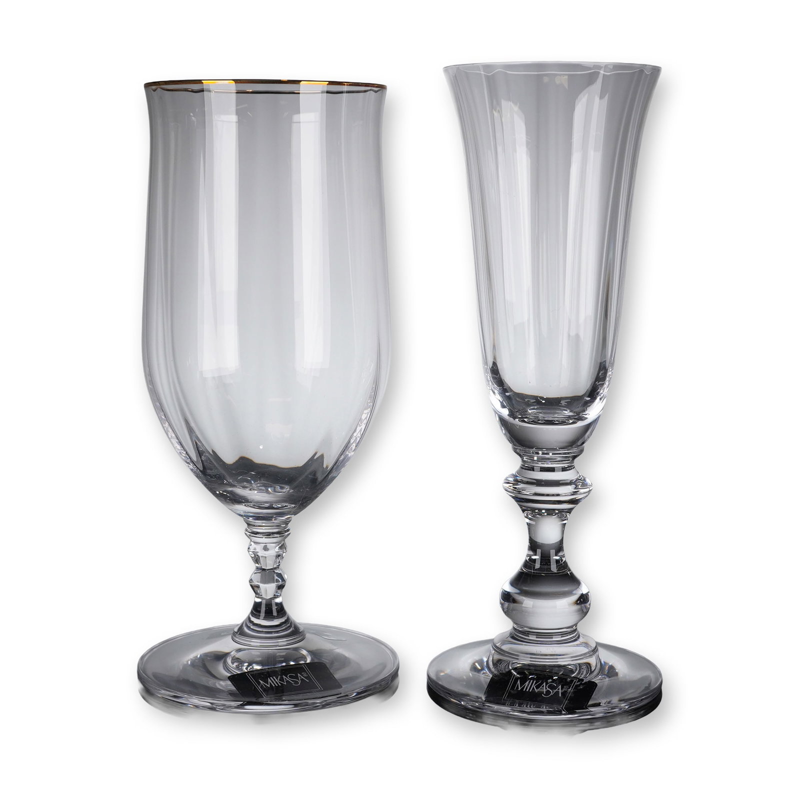 2pc Mikasa Crystal Iced Tea and Champgane Glasses: A group of Mikasa crystal stemware items consisting of one iced tea glass in the Sonata Gold pattern and one champagne flute in the French Countryside pattern. Both pieces are crafted from clear cryst