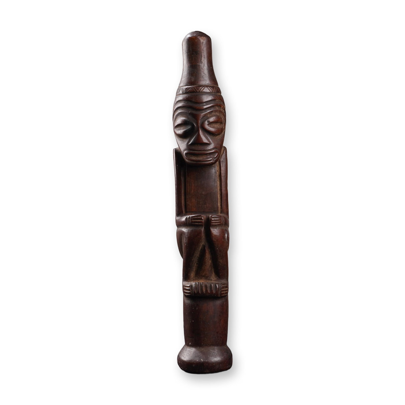African Wood Carved Seated Figure: This wood carved sculpture depicts a stylized human form in a seated posture. The figure is hand-carved from a single block of dark-stained solid wood and is positioned atop a cylindrical pedestal