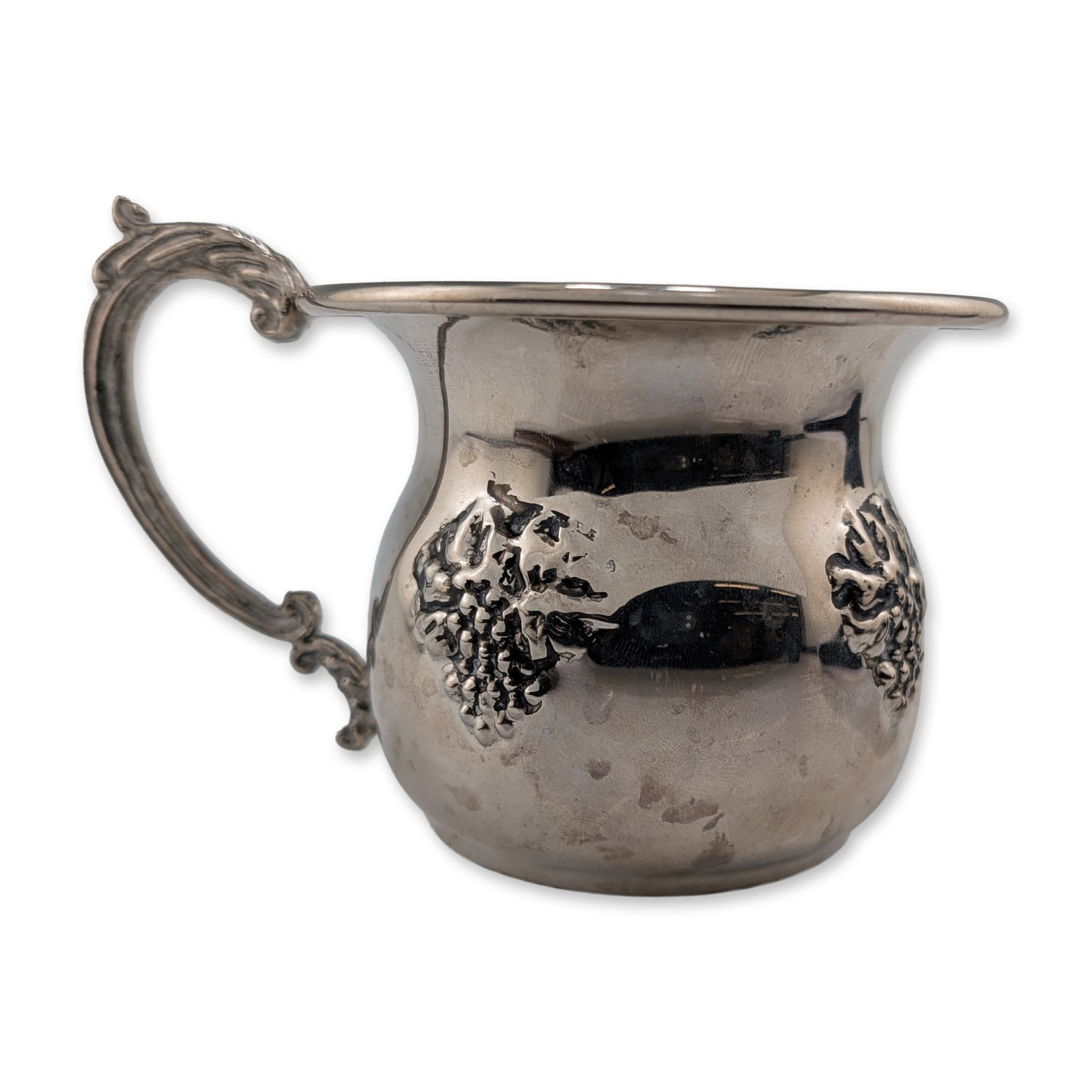 Silver Plated Grapevine Motif Creamer: Deaturing a bulbous body decorated with two cast relief grape clusters. The piece is designed with a flared rim and an ornate scrolled handle with acanthus leaf motifs, supported by a circular