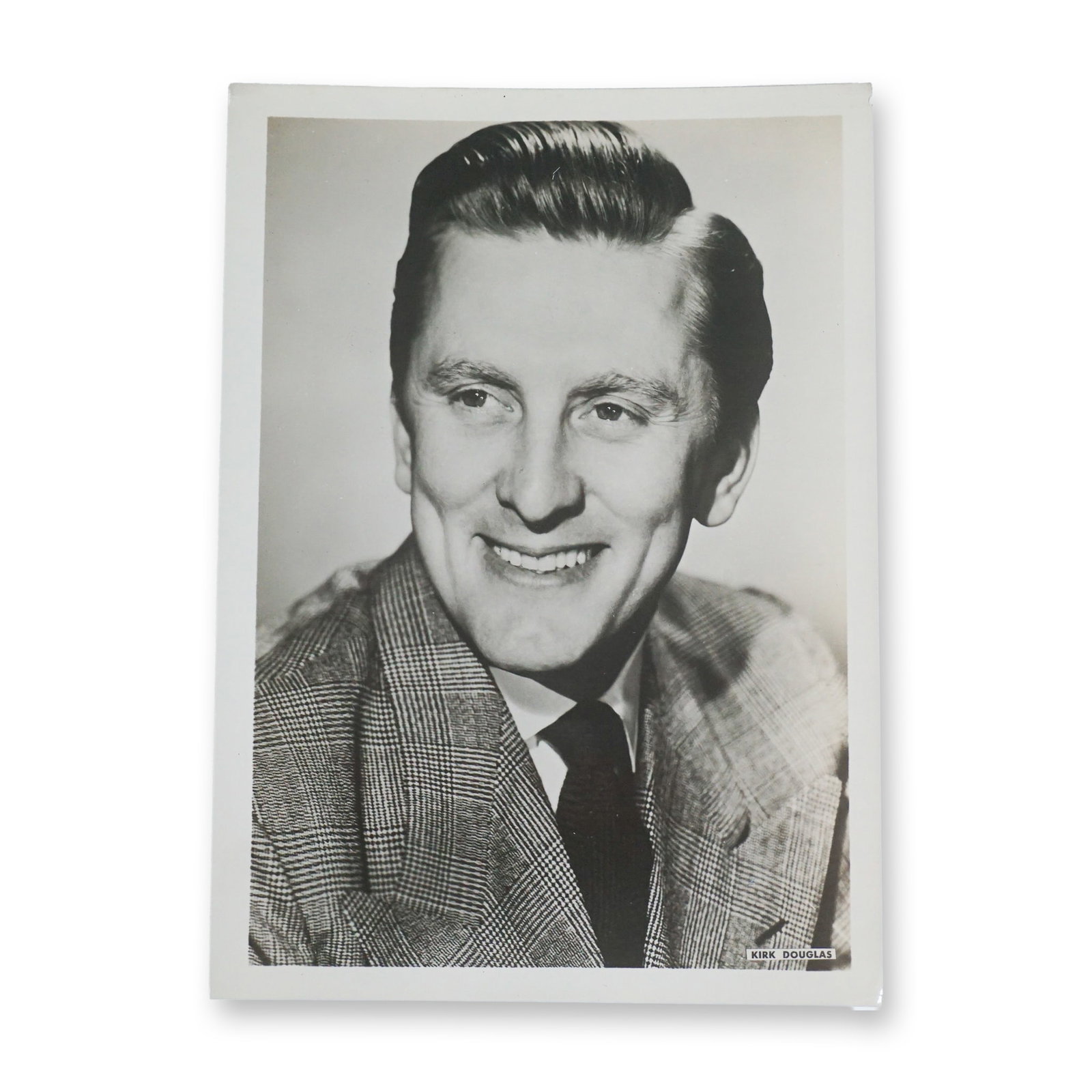 Kirk Douglas Vintage Promotional Photograph: Vintage black-and-white promotional photograph of Kirk Douglas, the legendary actor known for his powerful performances in classic films such as Spartacus, Paths of Glory, and Champion. This striking 