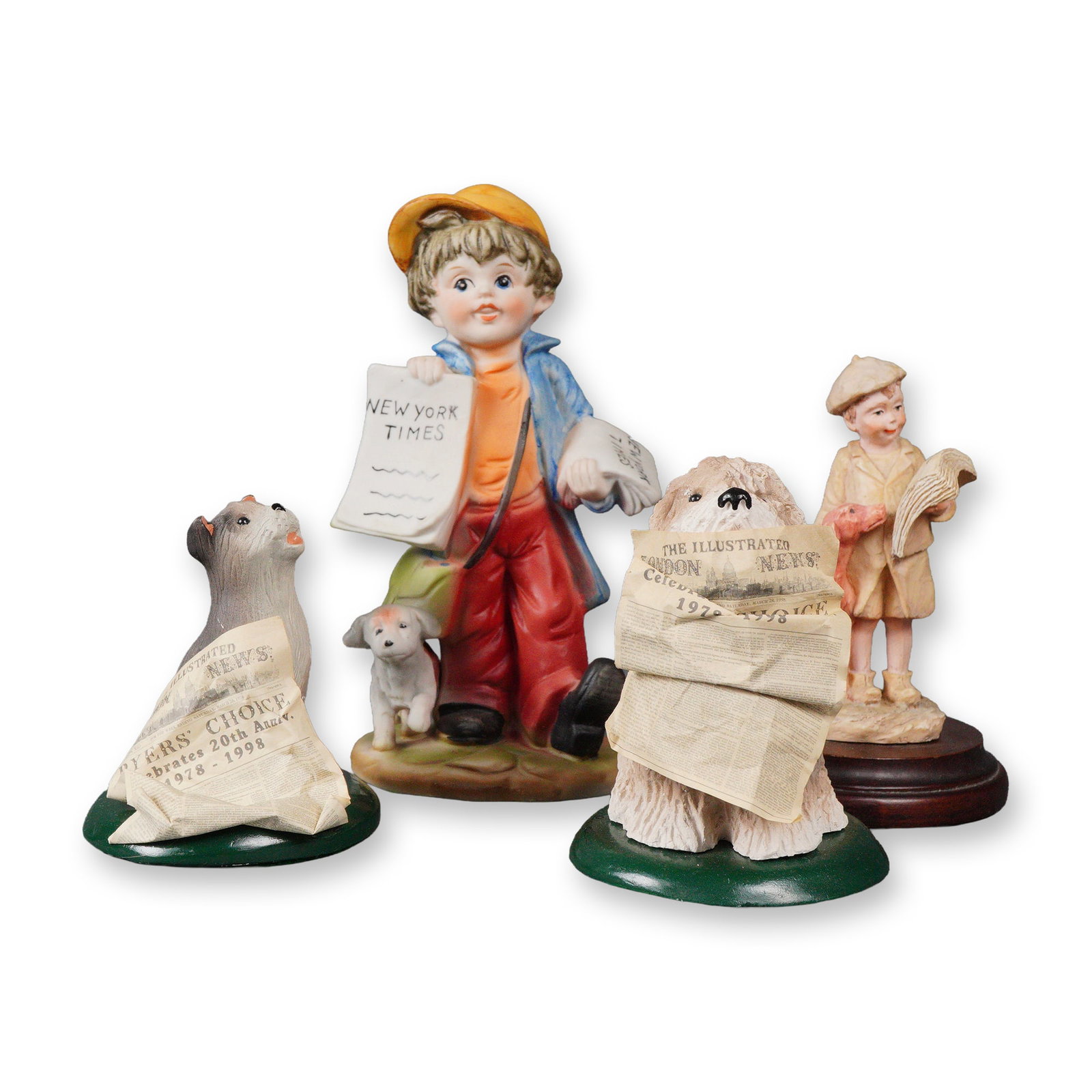 A Group of Four Newspaper-Themed Figurines, including a Capodimonte-Style: A group of four decorative figurines, all unified by a newspaper theme. The central piece is a polychrome figure of a young newsboy in a yellow cap, holding a newspaper prominently marked NEW YORK