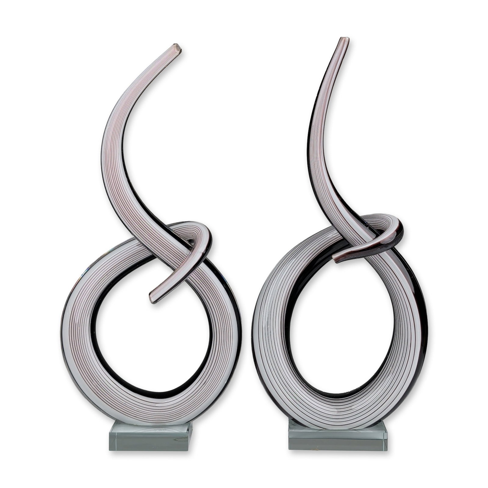 Pair of Contemporary Linear Cane Abstract Glass Sculptures: Pair of contemporary hand-blown studio glass sculptures in a looped form with a tapering tail. Hand-blown construction utilizing a linear cane technique with alternating stripes of opaque white and