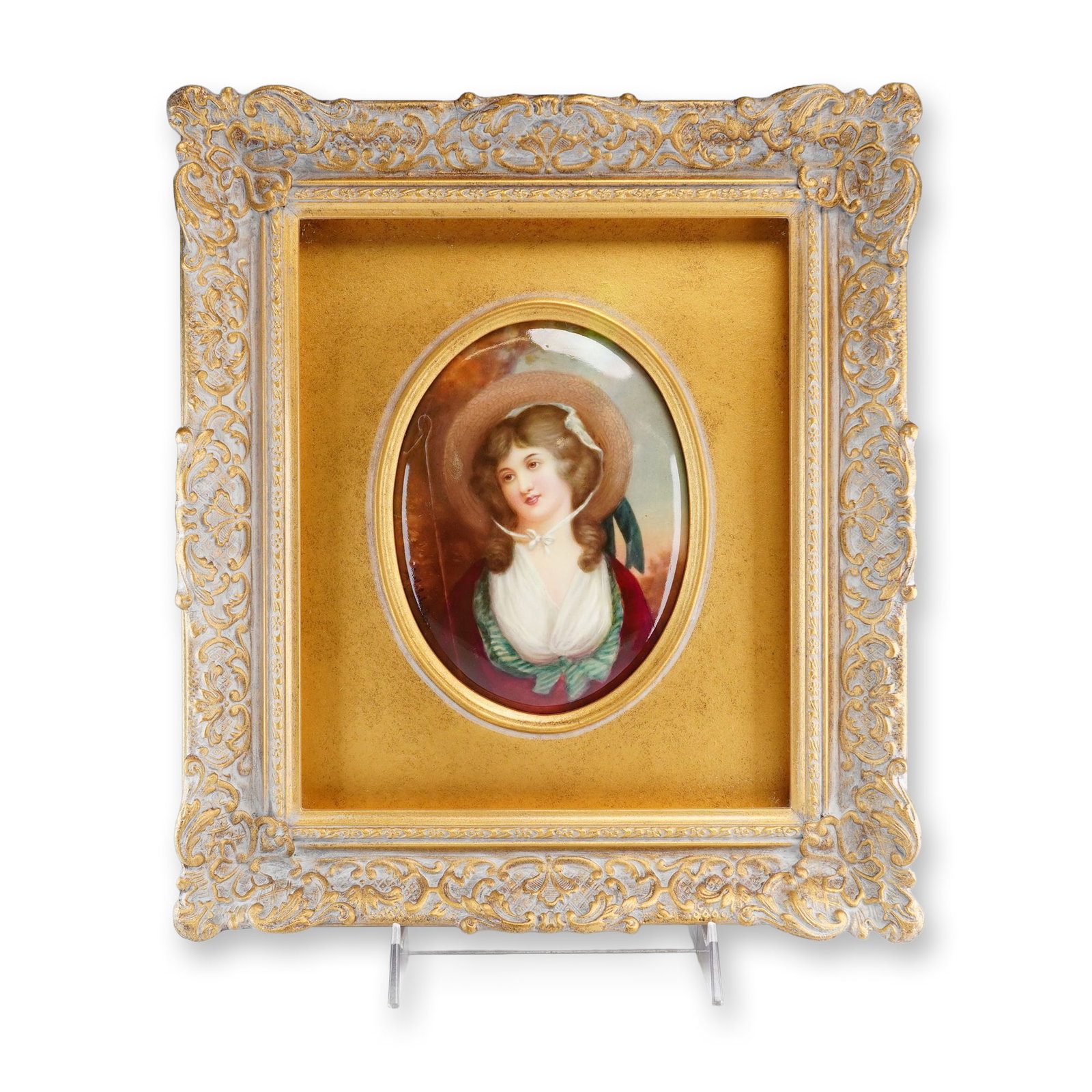 Framed Leslie Johnson Hand-Painted Plaque, Shepherdess: A hand-painted porcelain plaque featuring an oval enamel portrait of a young woman in the guise of a shepherdess. The subject is depicted wearing a wide-brimmed straw hat with a white ribbon, a red ja