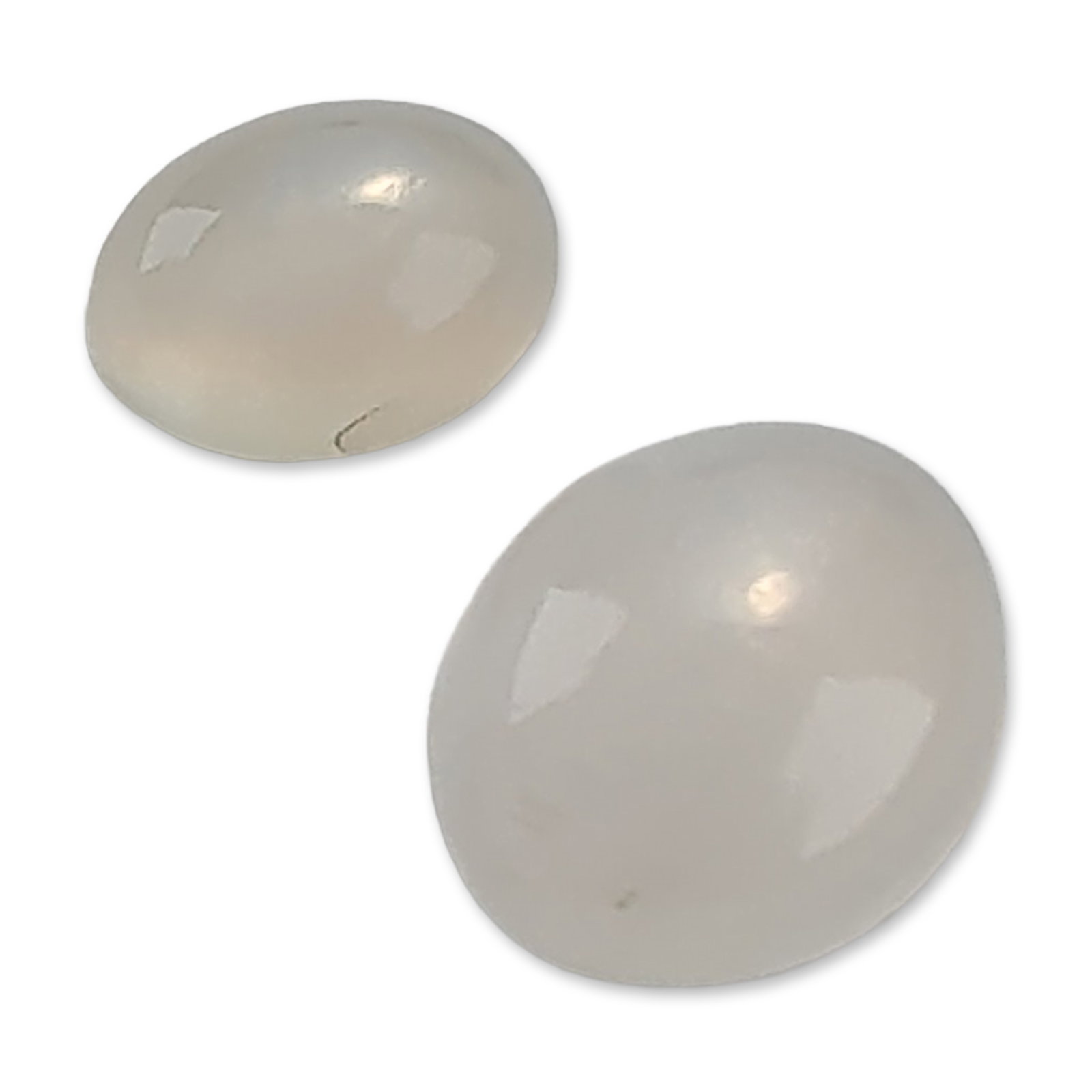 Pair of White Moonstone Cabochons: Pair of loose white moonstone gemstones . The stones are oval-cut cabochons with flat bases, featuring a translucent milky white color and characteristic soft adularescence. The lot consists of one