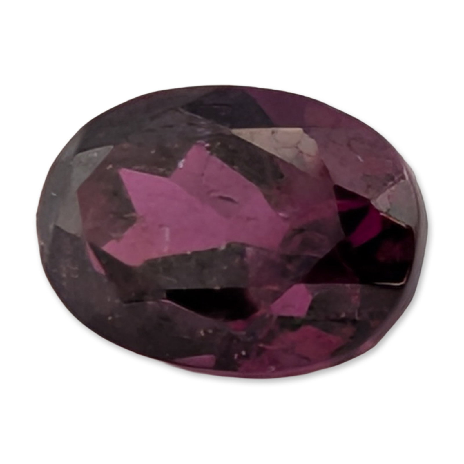 Loose Oval Cut Purple-Red Rhodolite Garnet Gemstone: Appears to be rhodolite garnet. Loose oval faceted gemstone in purple-red, featuring a deep pavilion and visible internal inclusions including veils and crystalline structures. 7.3 x 5.1 mm 1.3 ct. Di