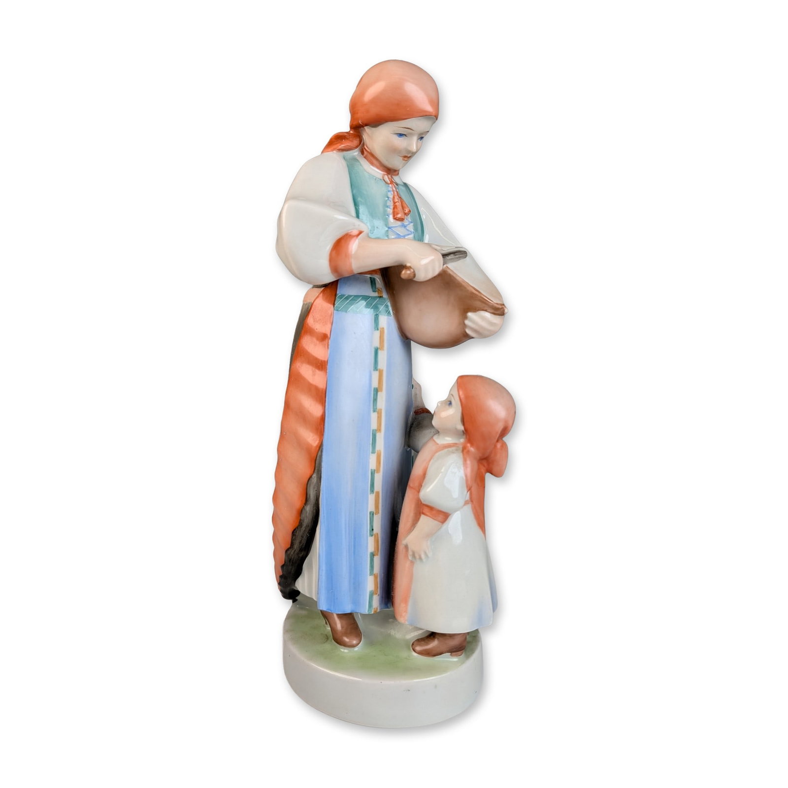 Polychrome Porcelain Mother and Child Folk Figurine: Hand-painted glazed porcelain figurine depicting a woman and small child in traditional folk costume. The woman is portrayed standing, wearing a red-orange headscarf, a white blouse with a teal vest, 