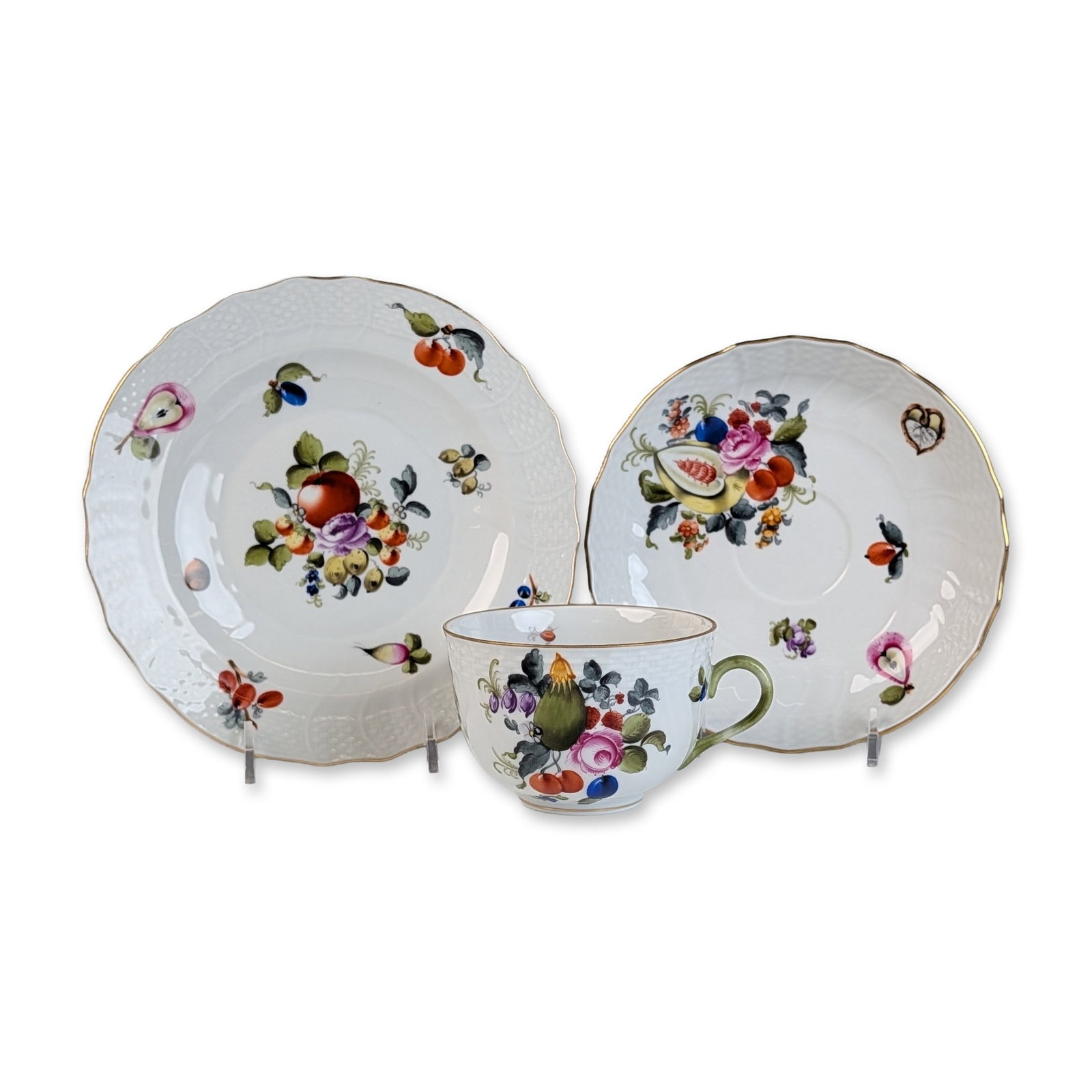 Herend Hungary Fruits and Flowers Porcelain Trio: Herend Hungary porcelain tea trio in the Bouquet de Fruits (BFR) pattern, including a teacup, saucer, and dessert plate. Each piece is crafted in the Altozier shape, characterized by a scalloped rim w