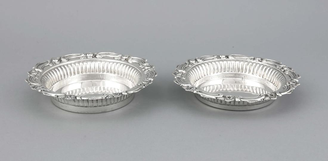 Paar Flaschenuntersetzer, wohl Niederlande, Anf: Pair of bottle trivets, probably Netherlands, early 20th cent., hallmarked silver, rimwith floral relief decoration, Ø 17.5 cm, approx. 324 g German Translation: Paar Flaschenuntersetzer, wohl Nieder