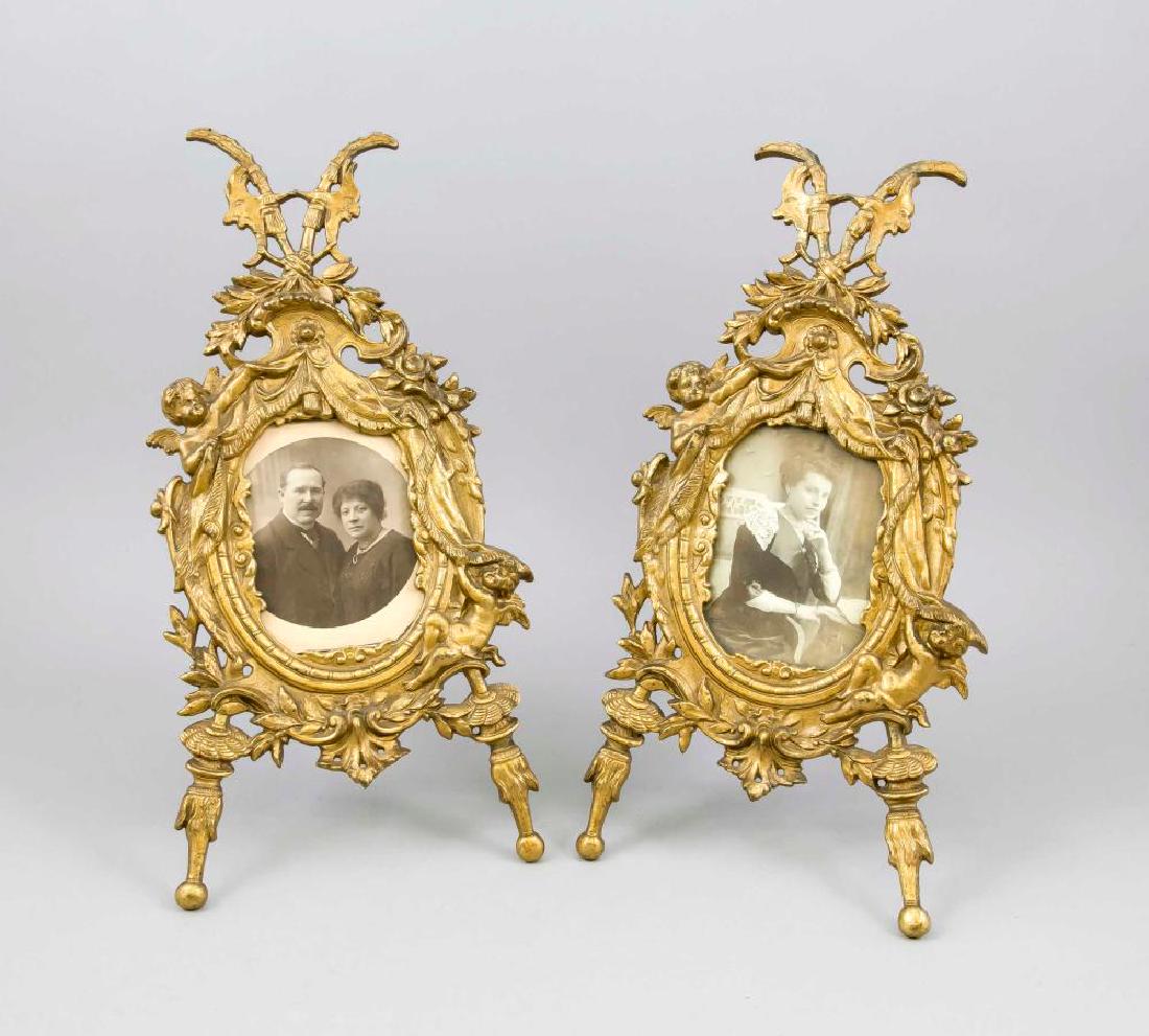 A pair of histo: A pair of historicism photo frames, c. 1900, gold-plated metal casting (bronze?). With eclectic ornaments overgrown, oval frame, partly durchbr. gearb., back fold-out support, each with black and whit