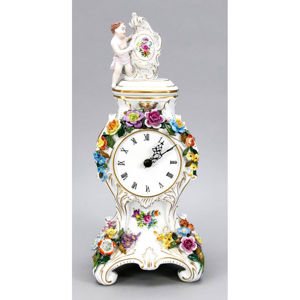Table clock, Dresden, 20t: Table clock, Dresden, 20th century, rococo shape, crowned by putto with a cartouche, richly set with plastic flowers, quartz clockwork, clock face with Roman numerals, h. 45 cm