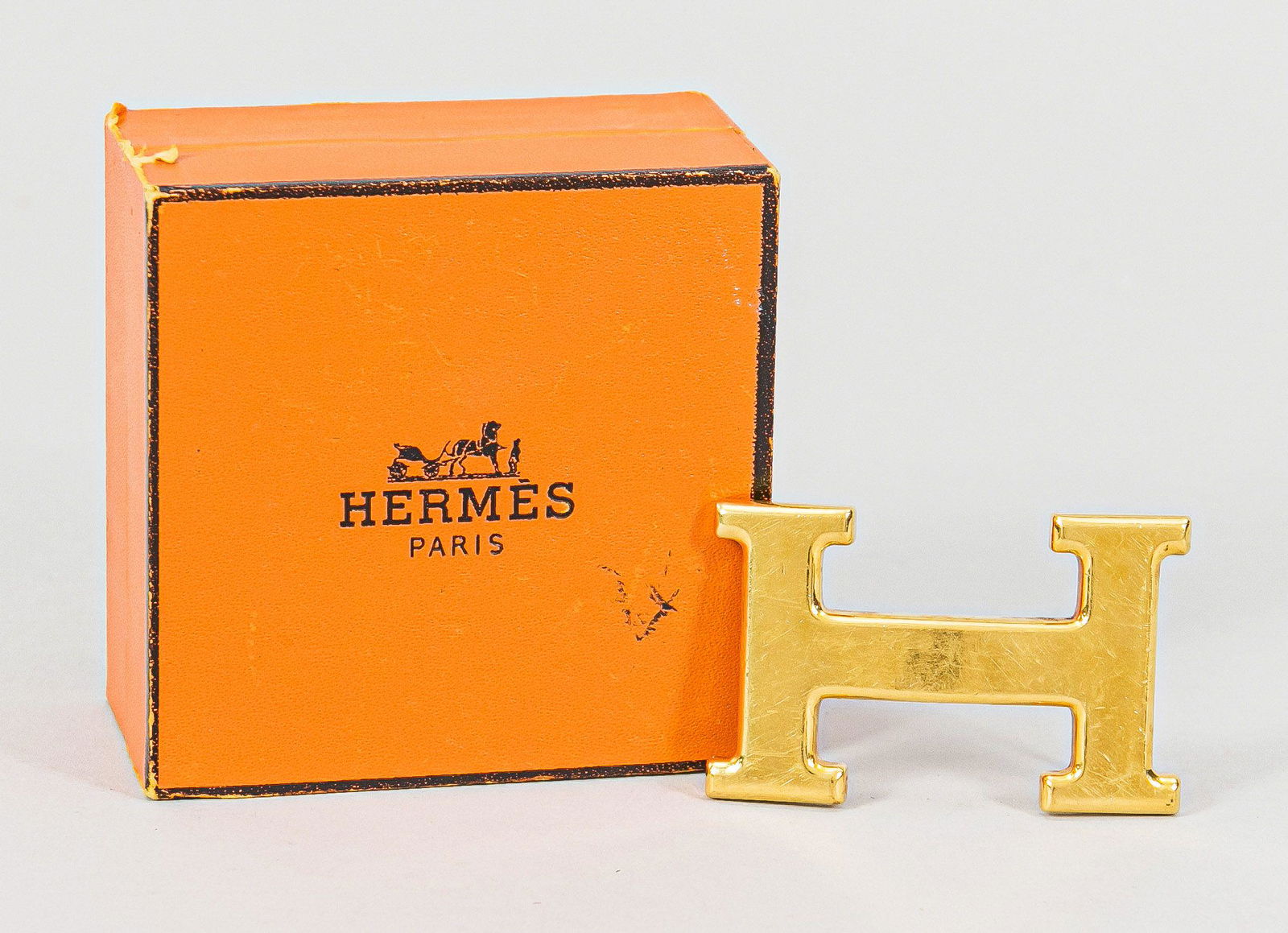 Belt buckle by HermÃ¨s, golden ''H'': Belt buckle by HermÃ¨s, golden ''H'', traces of use, with HermÃ¨s box 8 x 8 x 4 cm