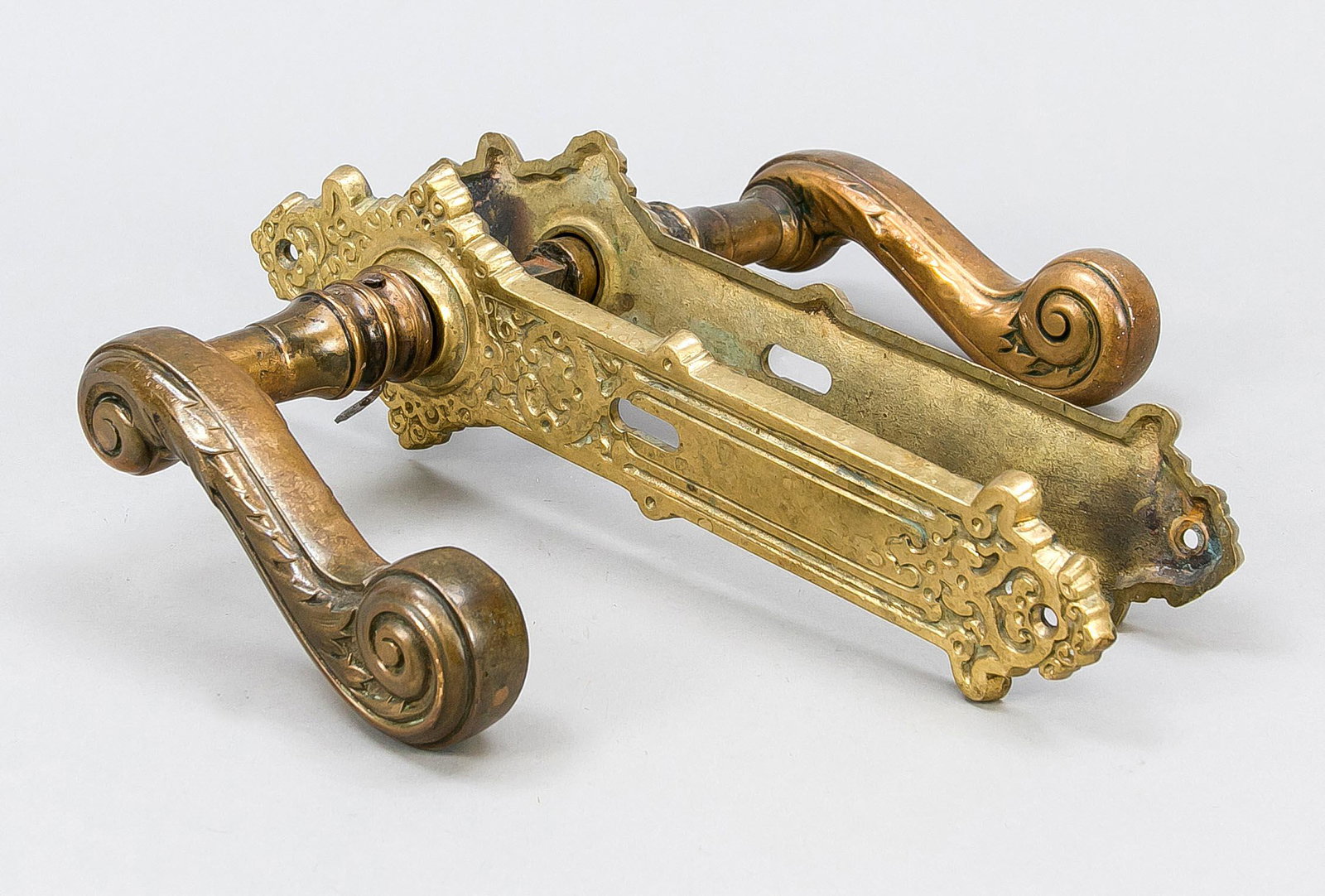 Handle set for a front door, l: Handle set for a front door, late 19th century, brass. Fitted curved and ornamented striking plates, large volute handle, slightly rubbed, h. striking plate 29 cm.