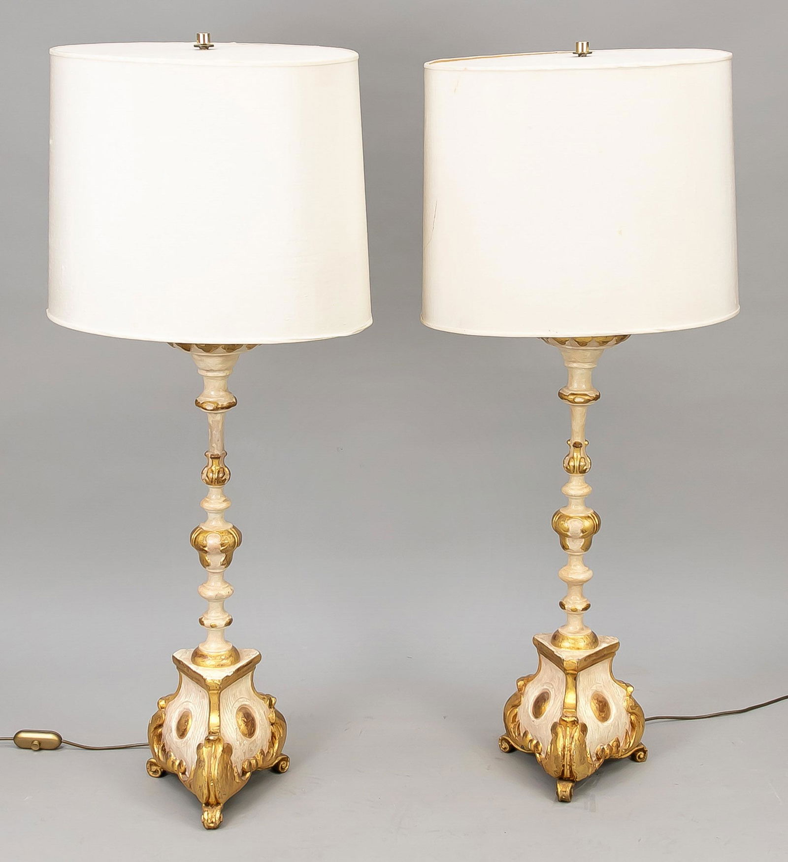 Pair of floor lamps with baroque: Pair of floor lamps with baroque feet, probably 18th century, tripod foot and balustraded shaft made of wood, white and gold painted. Oval lampshades made of crÃ¨me white fabric, h. 115 cm.
