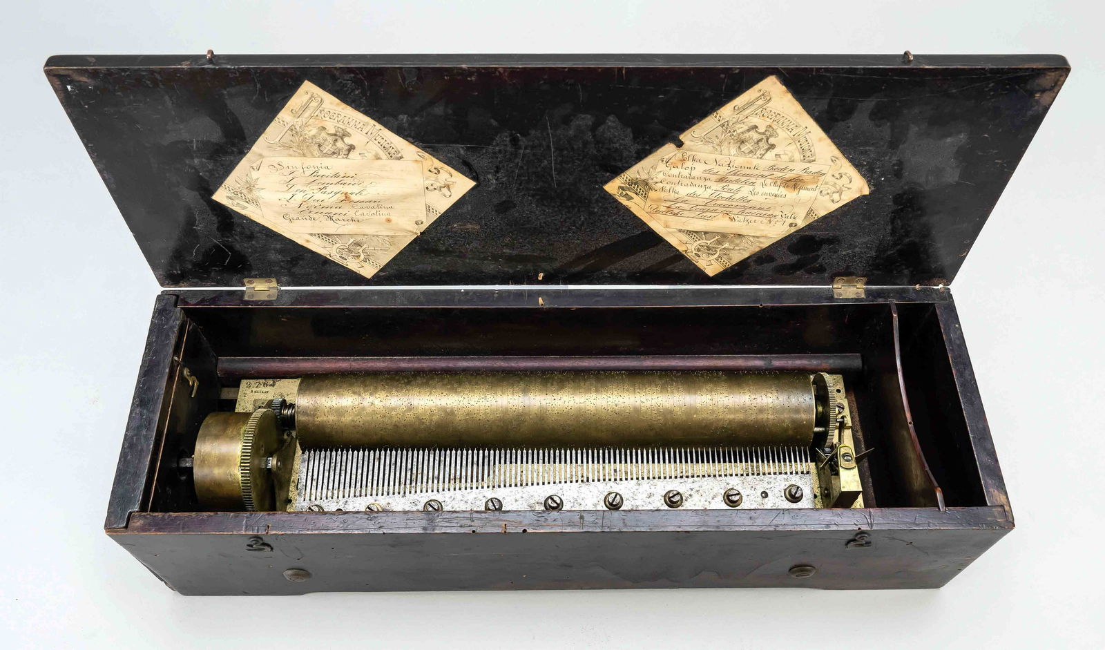 Large drum music box, 19th cen: Large drum music box, 19th century, in the hinged lid 2 paper stickers with the musical program. The sound comb is undamaged, mechanism works. Wooden case with black varnish, 13 x 50 x 16 cm.
