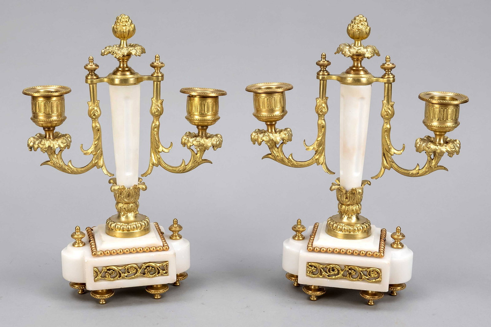 Pair of candlesticks, end of t: Pair of candlesticks, end of the 19th century, white marble pedestal on 6 feet. Shaft as marble column with 2 candelabra arms each as gilded bronze mount, vase spouts, h. 24 cm