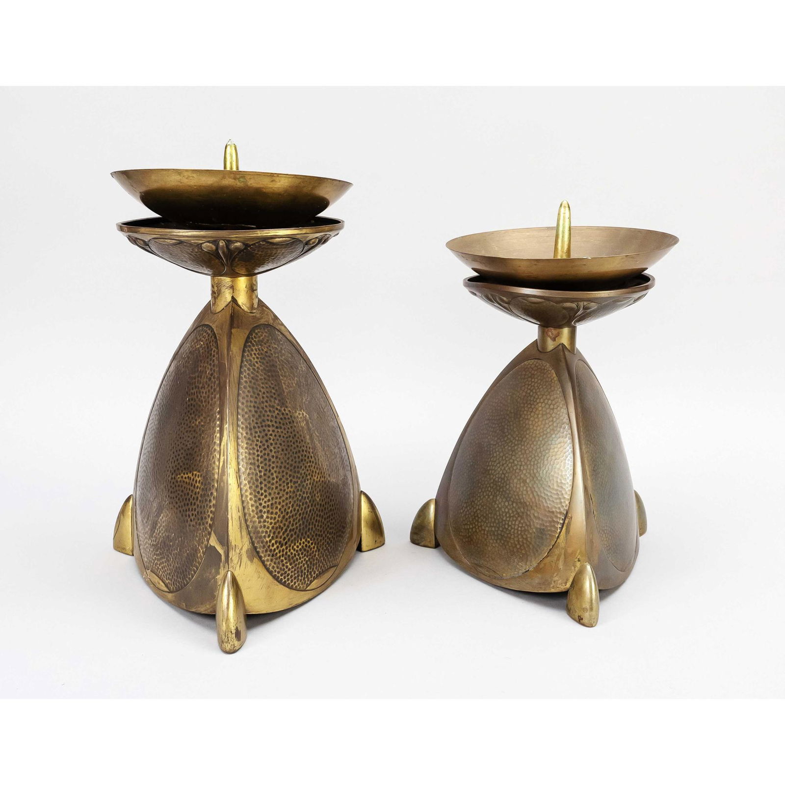 2 church candlesticks, mid 20th ce: 2 church candlesticks, mid 20th century, brass. Large, triangular shaped body, oval decoration similar to hammer blow, each with movable drip tray. H. 36 cm and 31 cm respectively