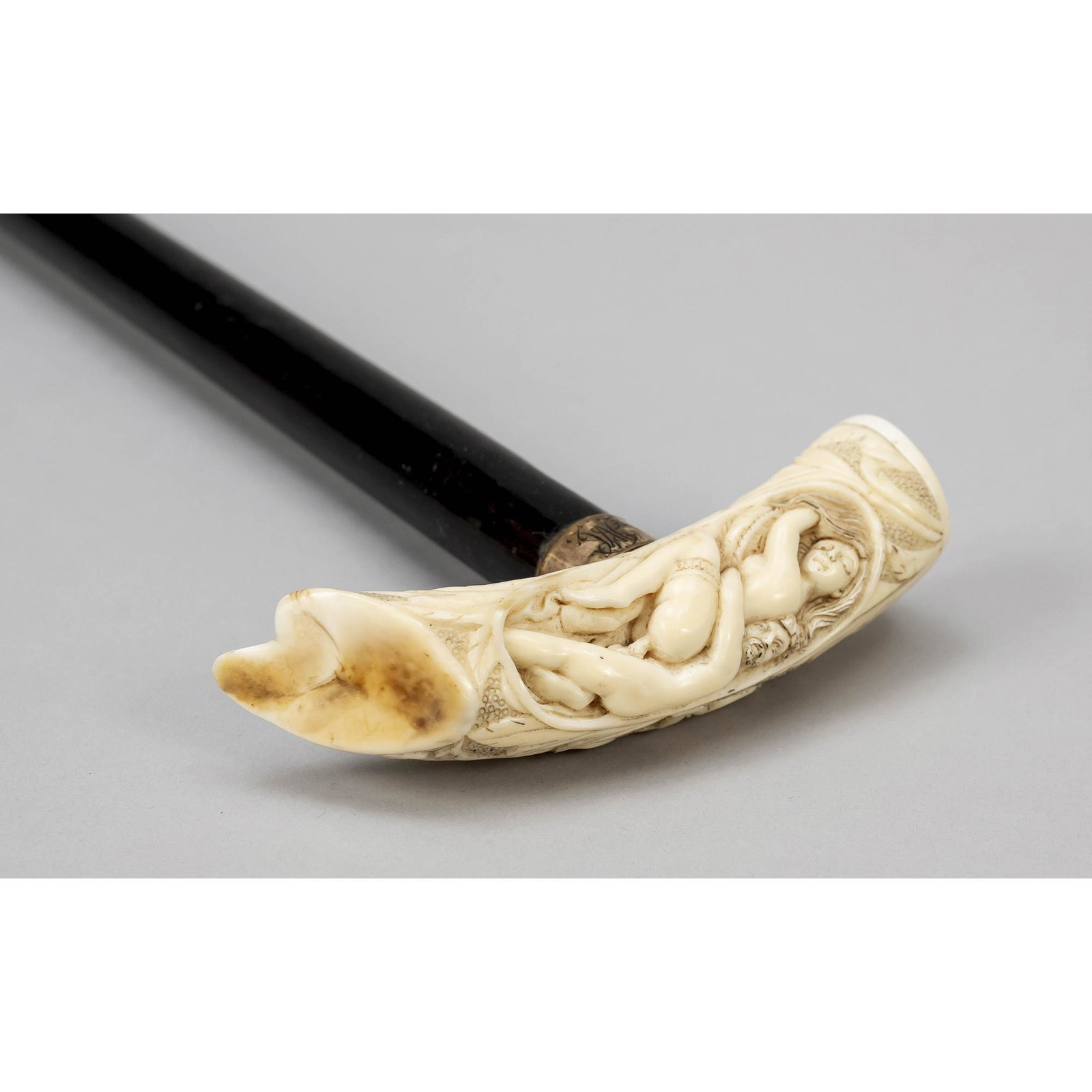 Erotic walking stick, probably Fran: Erotic walking stick, probably France 19th century, carving of hippopotamus tooth polished, foliage ornament, man and woman having a tryst, on the black stick metal cuff with initials, 13cm(knob), 90c