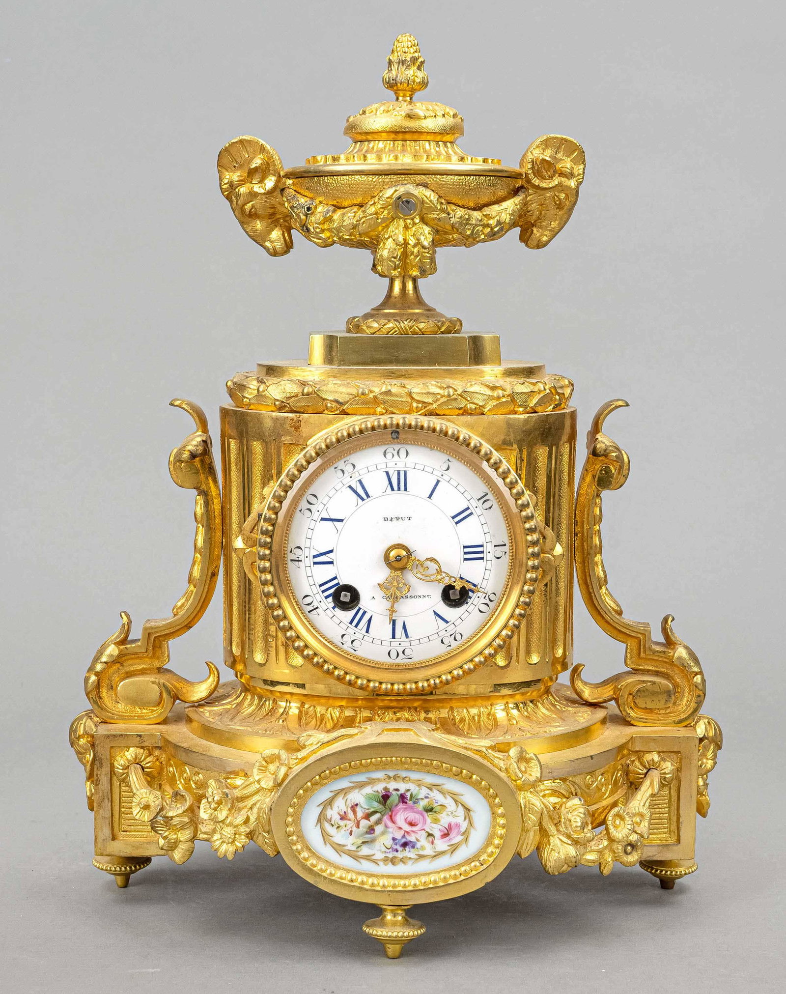 french. Table clock fire-gilt, 2nd half 19th c., decorated with vines and flowers, crowned with bowl: french. Table clock fire-gilt, 2nd half 19th c., decorated with vines and flowers, crowned with bowl and buck's head, with porcelain plaque polychrome painted with flowers, white enamel dial with blue