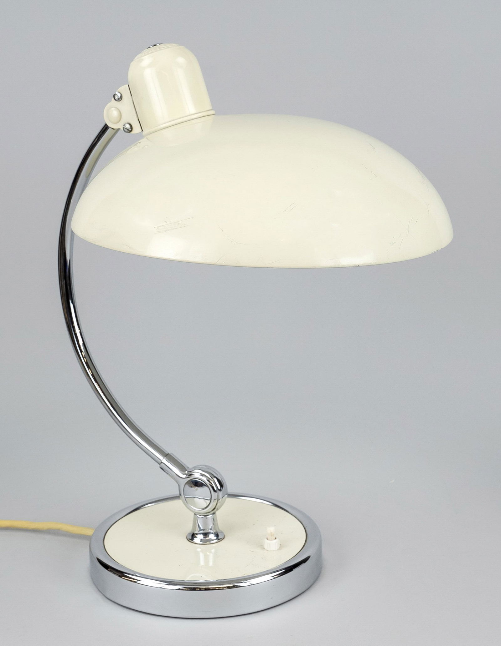 Table lamp Kaiser Idell model 6631, Germany, 1930s. Round base with chrome ring, curved and chrome: Table lamp Kaiser Idell model 6631, Germany, 1930s. Round base with chrome ring, curved and chrome candlestick arm (adjustable), dome-shaped lampshade made of cream-white painted iron sheet. Fabric co