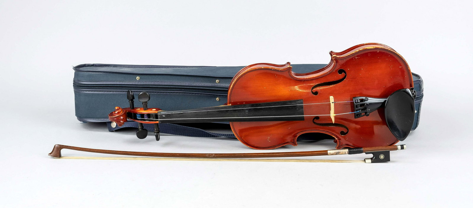 Violin with bow in soft case, Germany, 20th c. Violin marked ''Made in W. Germany'' on a label in: Violin with bow in soft case, Germany, 20th c. Violin marked ''Made in W. Germany'' on a label in the body, stringing not complete, l. body 33 cm. Bow with silver mounting, frog with mother-of-pearl e